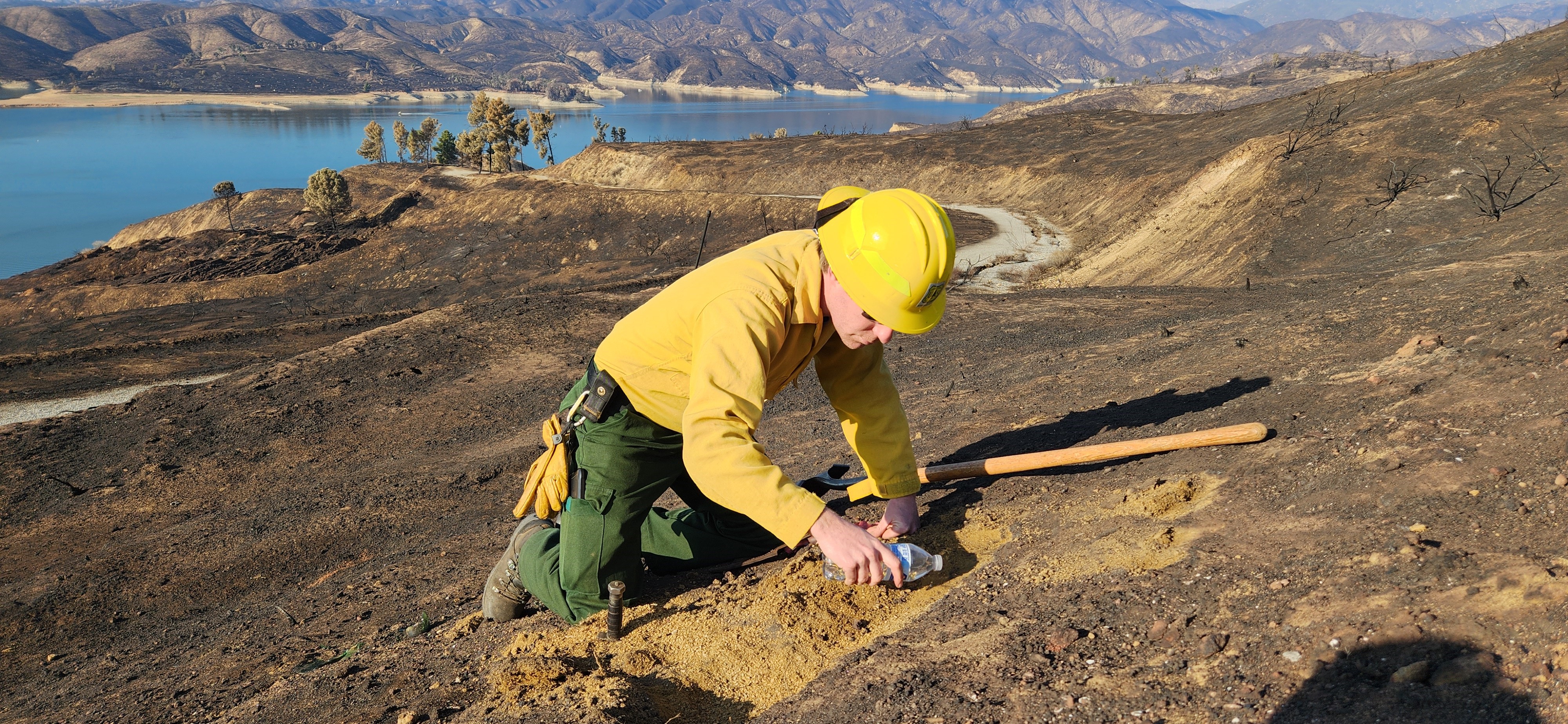 

						BAER Soil Scientist Curtis Kvamme pours water to test soil for water repellence in Hughes Burn Area
			