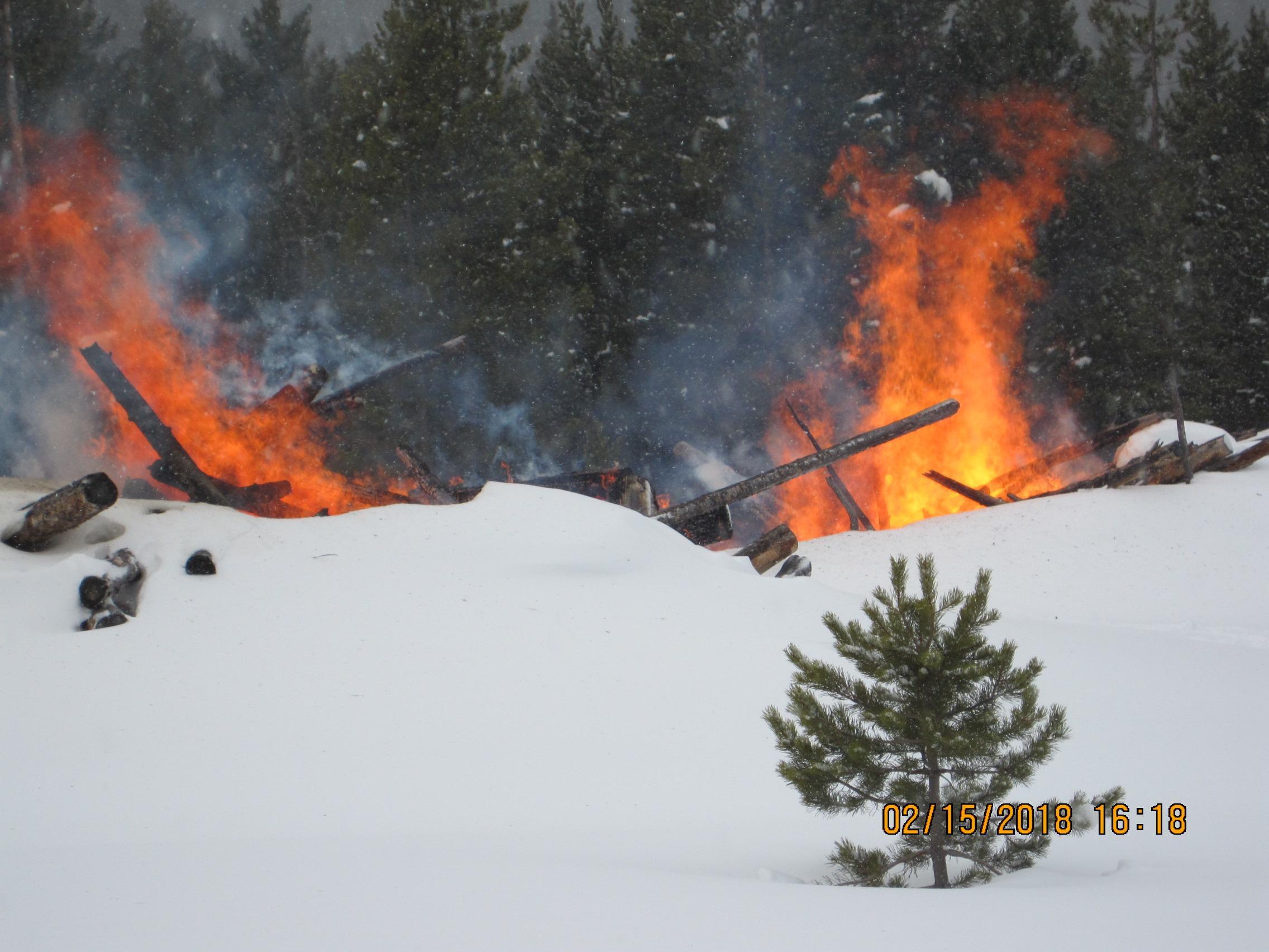 Pile burning in snow with smoke, flames