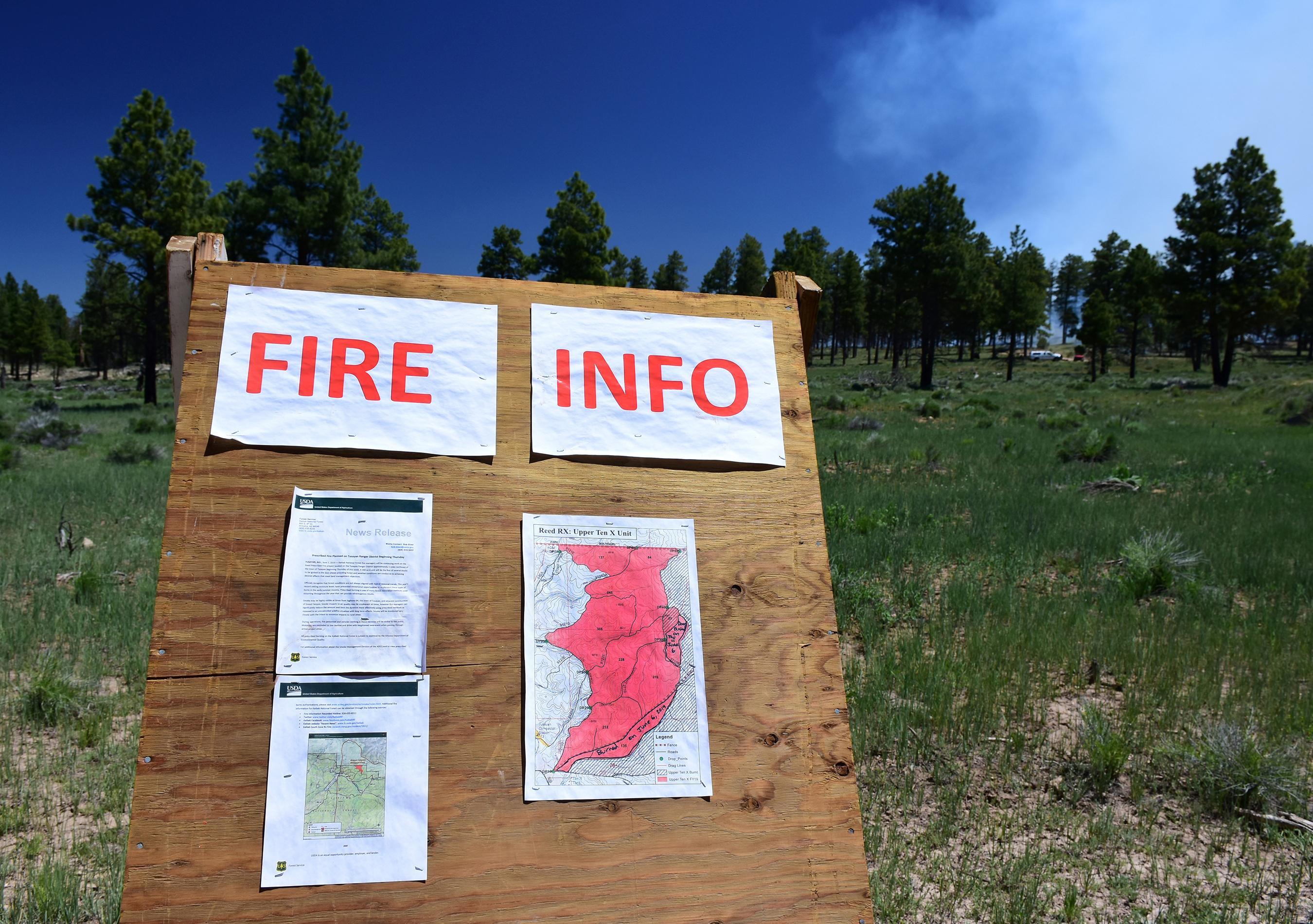Fire information board for the Reed Prescribed Fire burning in the background.