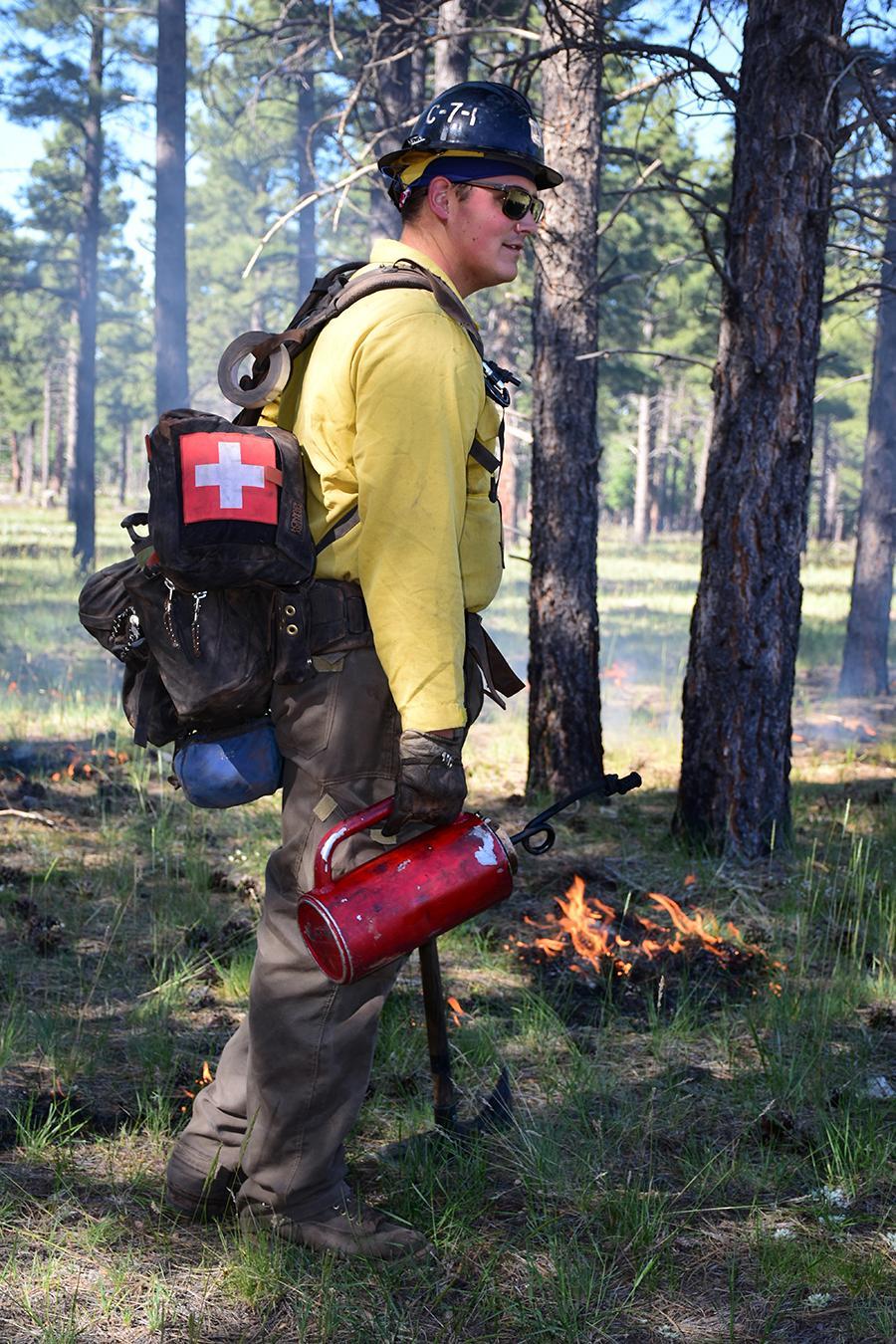 Firefighter lighting specific areas with drip torch.