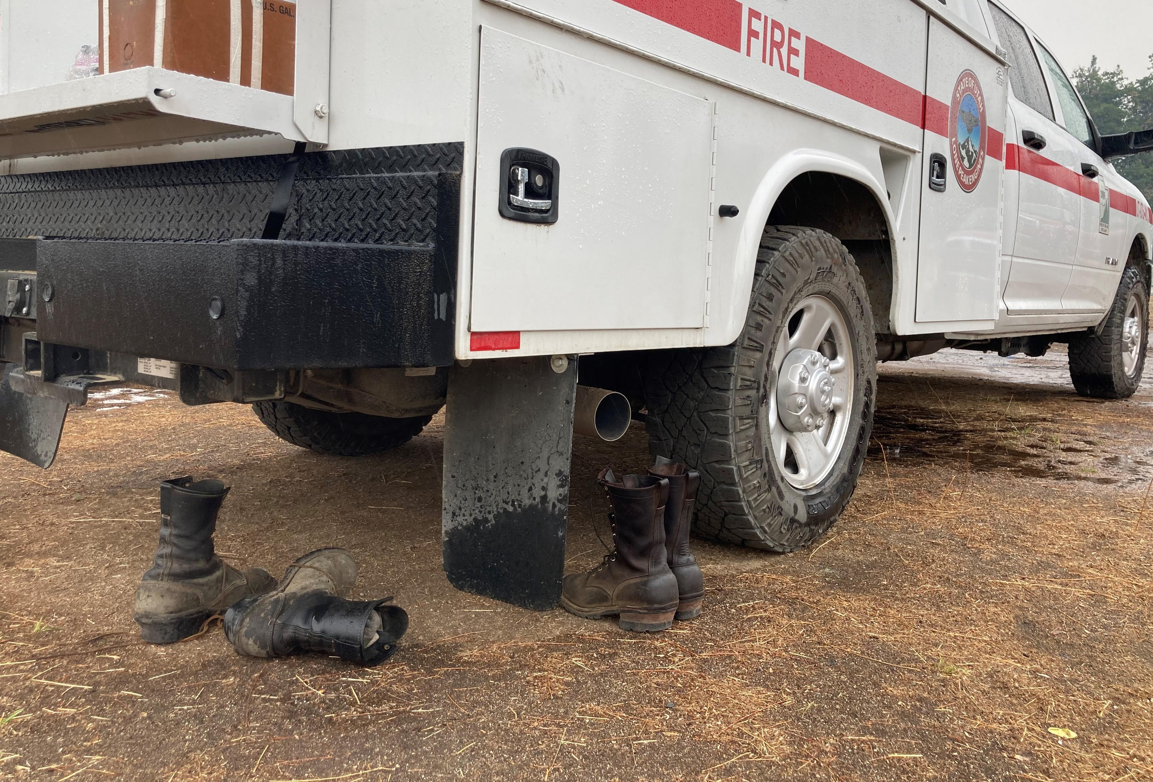 Two pairs of boots under a truck. 