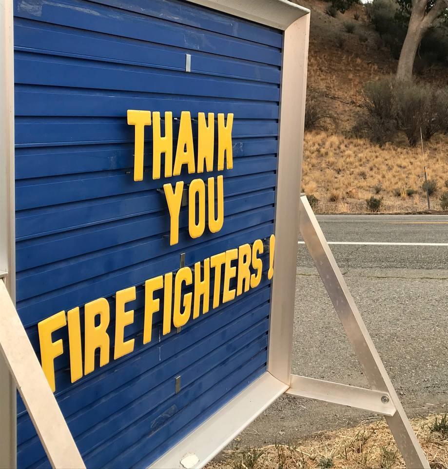 A blue sign with yellow letters reading Thank You Firefighters!