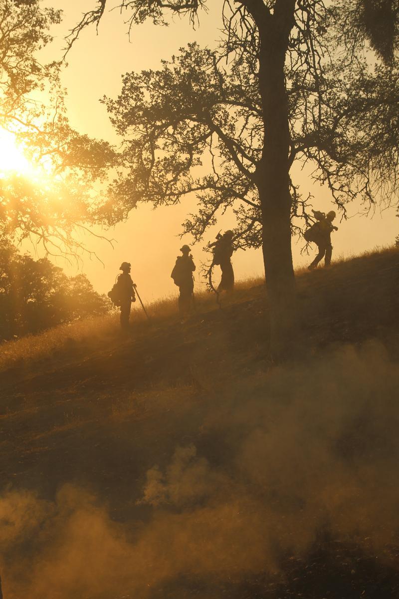 Firefighters hike along a ridge after containing a spotfire near Deer Creek Road.