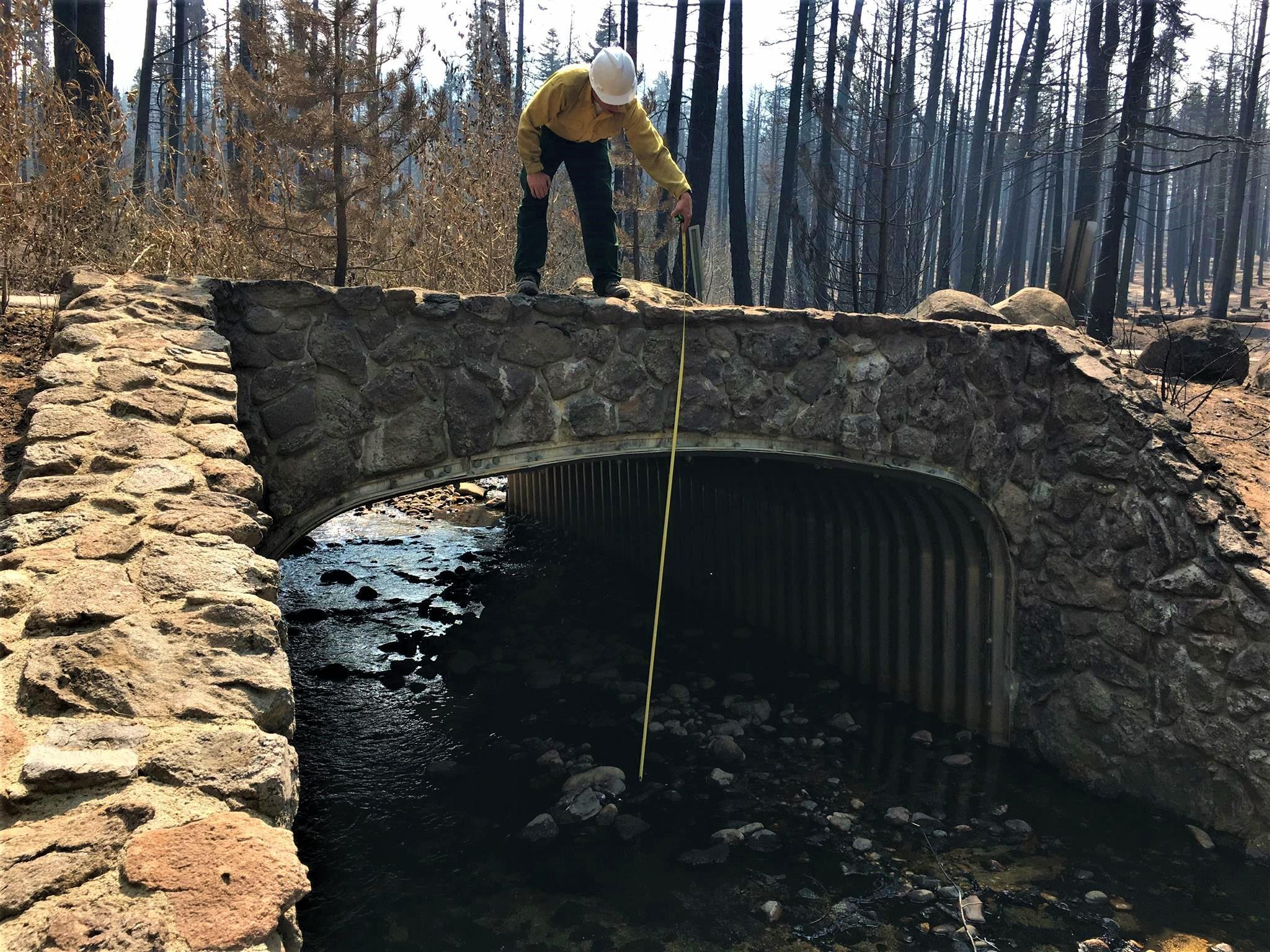 Assessing Bridge Clearance for IncreasedWaterFlows Photo showing BAER Road Engineer Assessing Bridge Clearance for Increased Water Flows in Caldor Burned Area