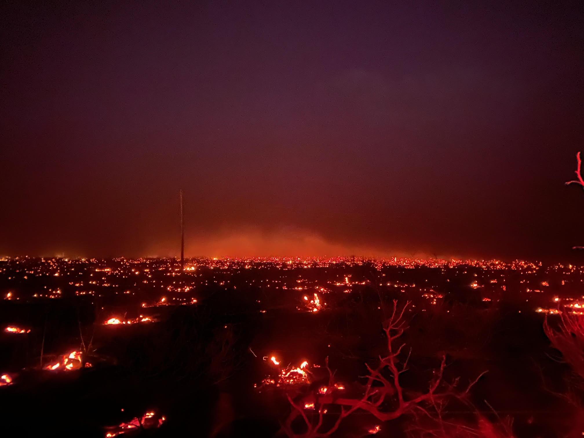 dark photo with widespread red glows from the fire moving through a recently harvested cornfield