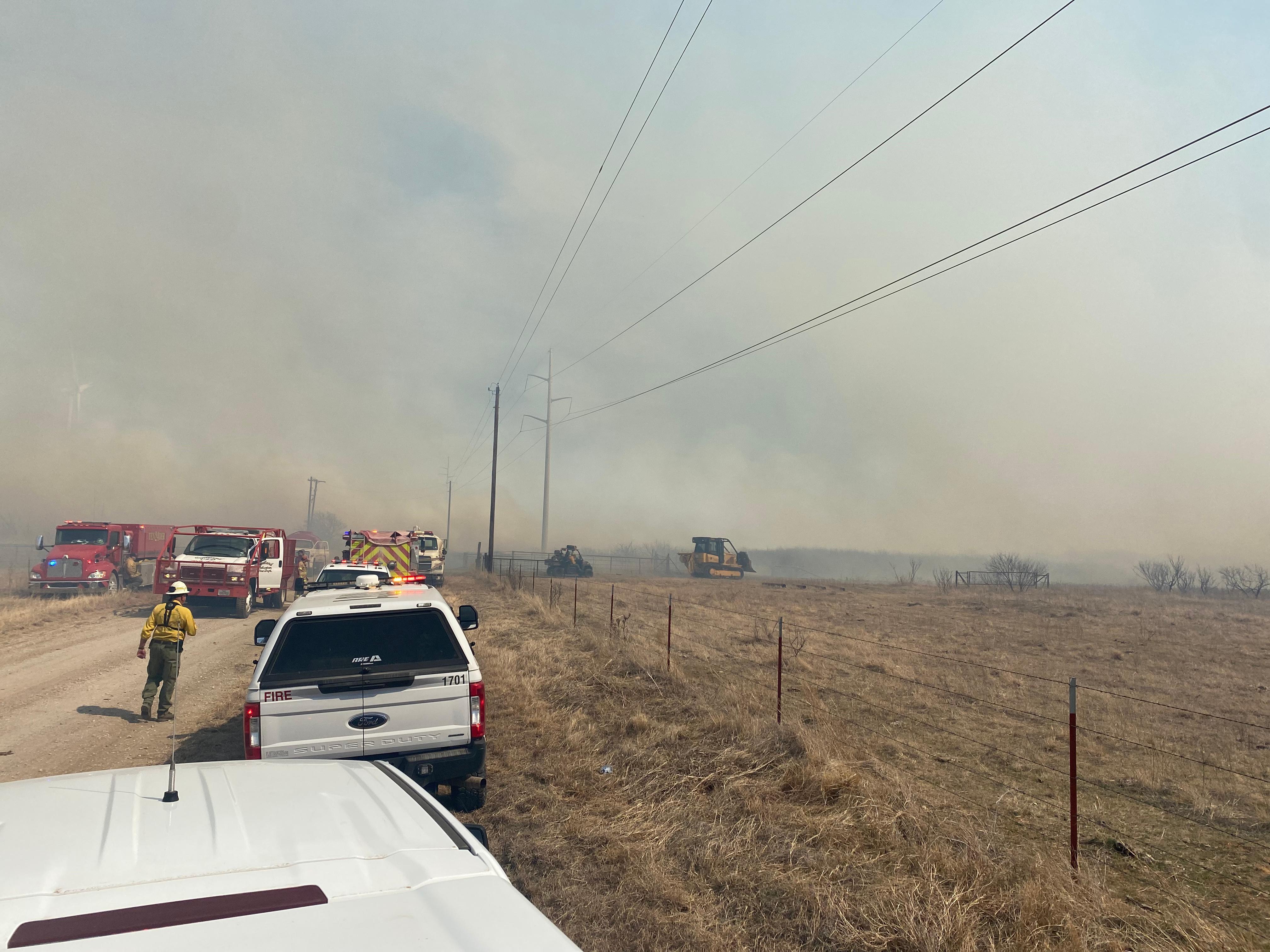 Fire trucks, fire fighters, and a dozer in the background