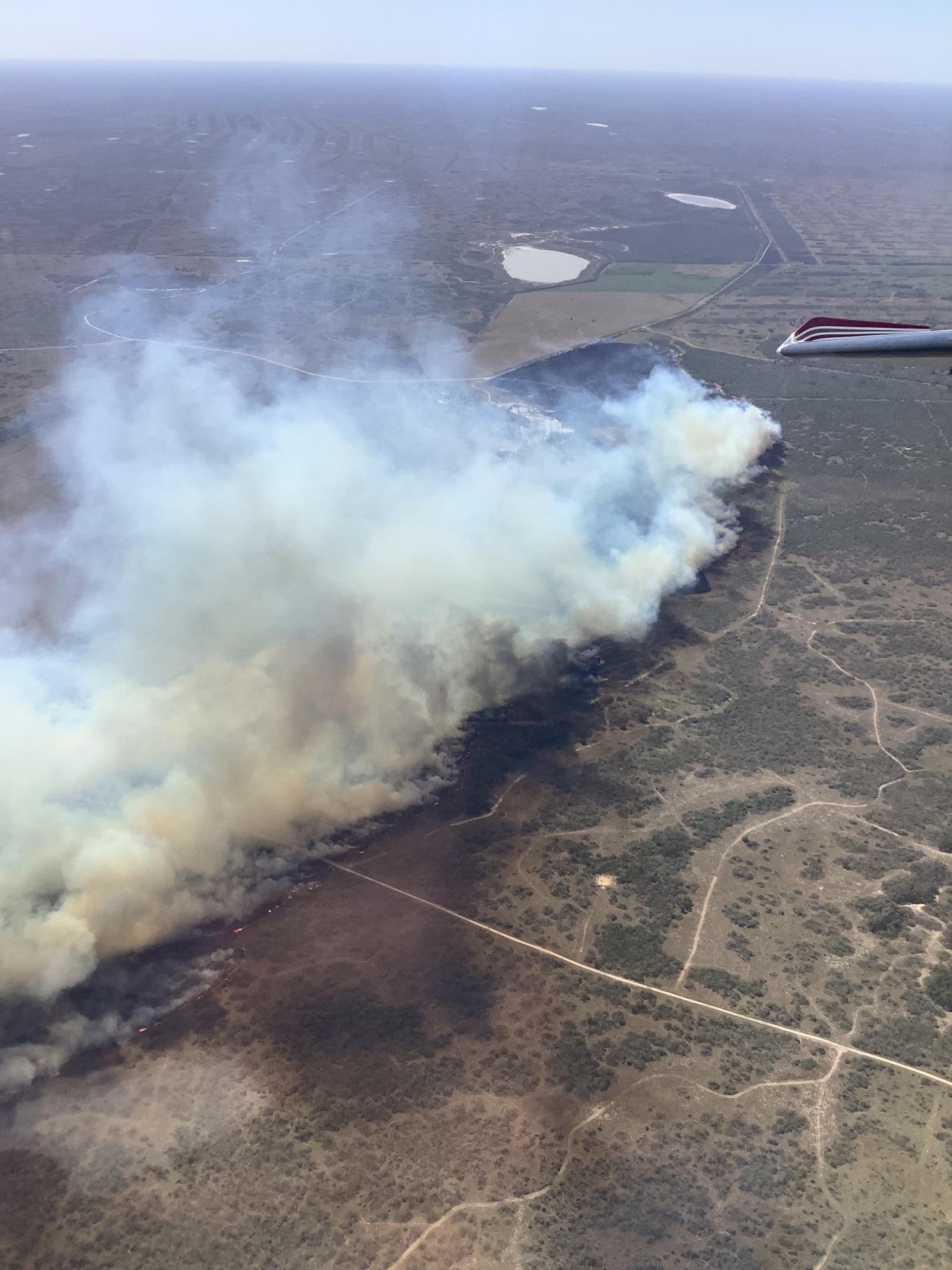 View from a plan of rural ranch land with white and grey fire plume