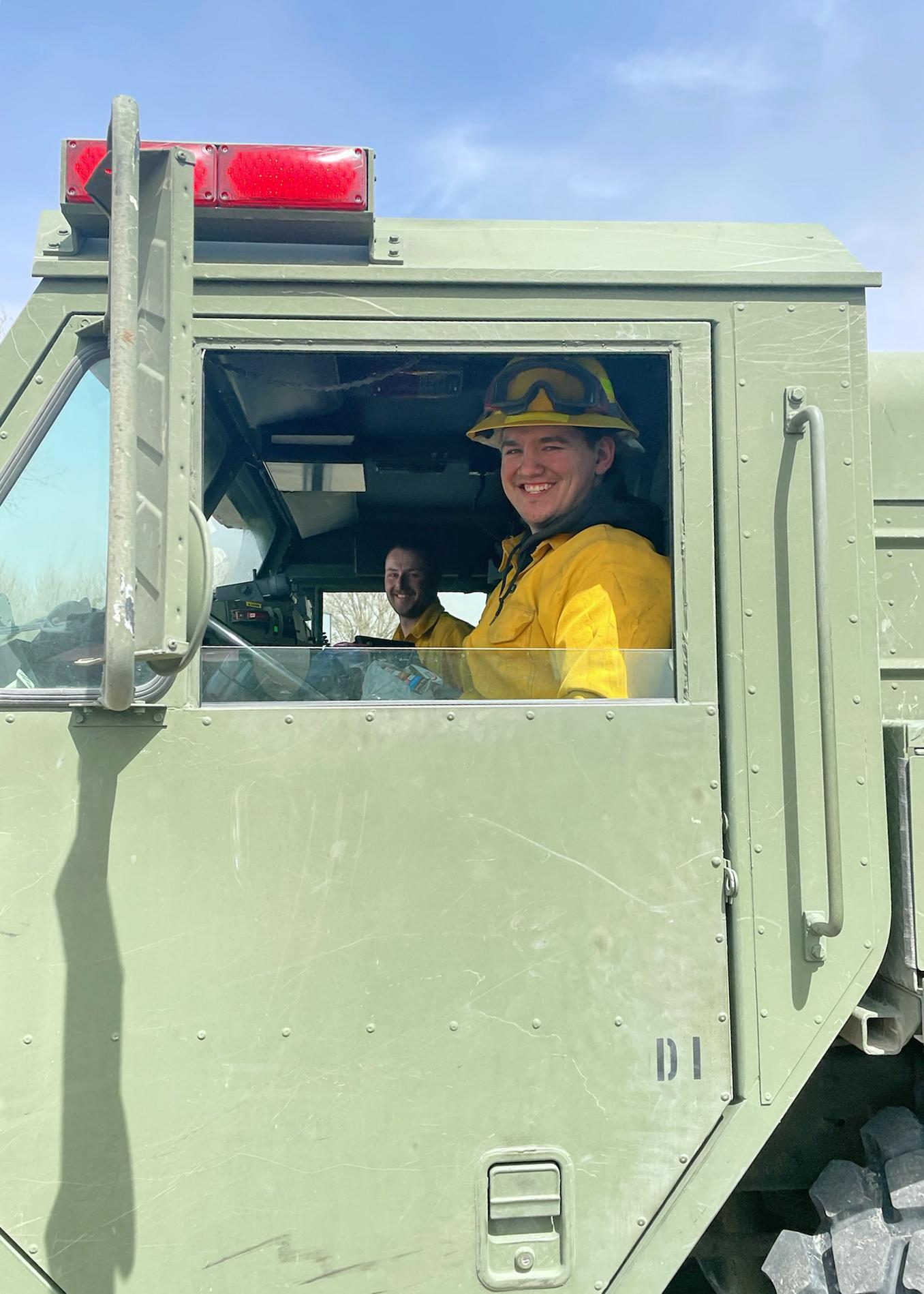 Spc. Seth Miller (foreground) and Staff Sgt. Gage Boyce (background) pause for a photo while operating the HEMTT-Based Water Tanker (HEWATT) near Cambridge today, where they have supported wildfire response the past four days. Boyce serves with the 281st