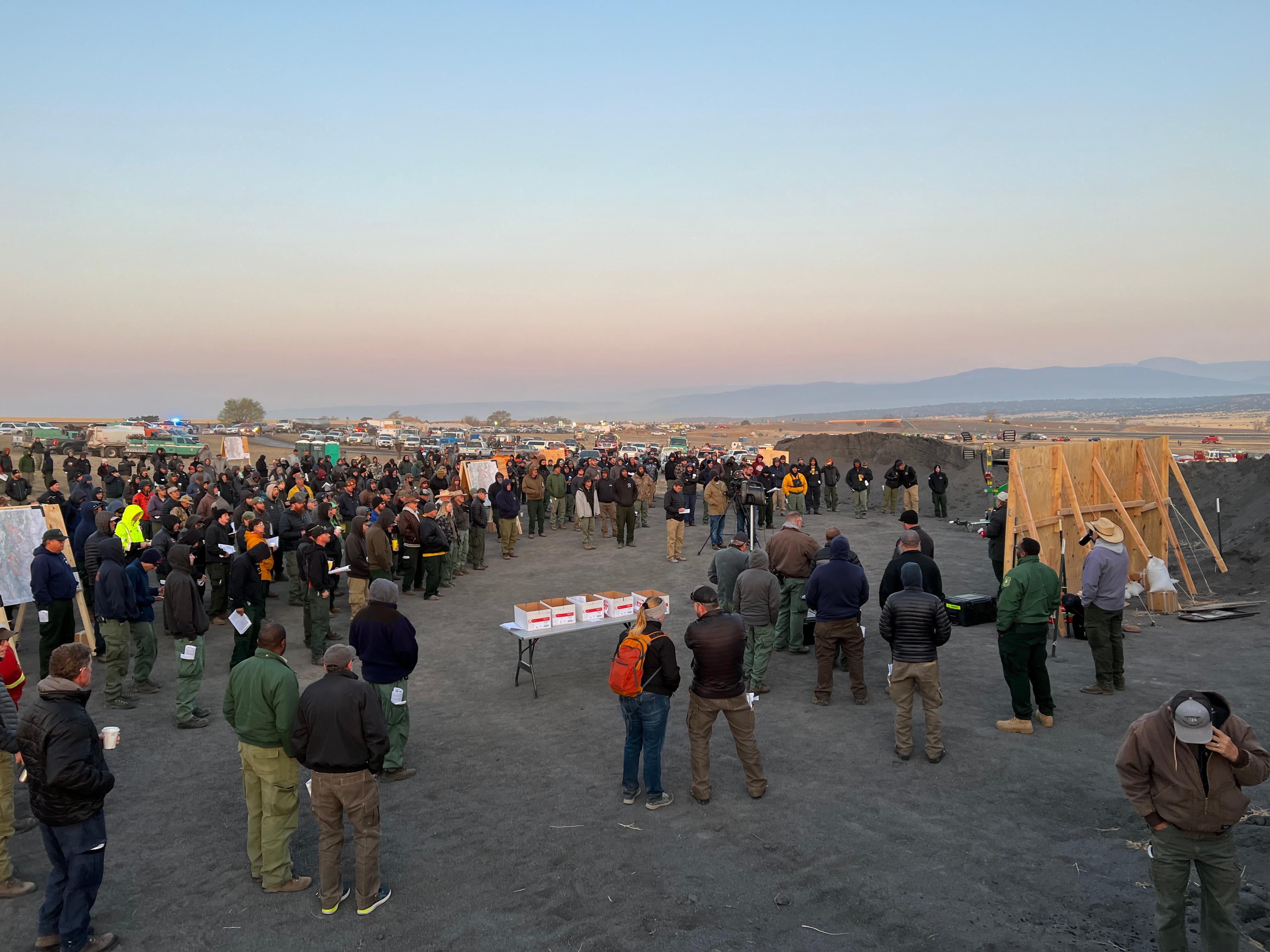 Firefighters gather for their morning meeting at a new fire camp along I-25 north of Las Vegas New Mexico on May 5, 2022.