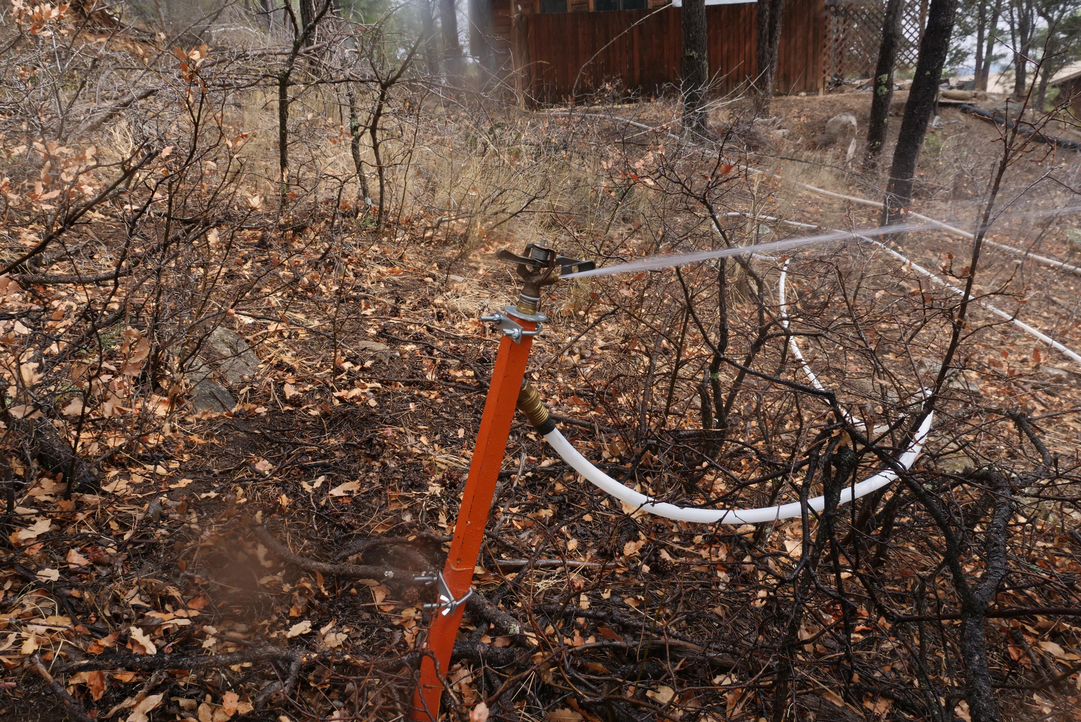 Sprinklers, powered by portable pumps and supplied by portable water tanks, are set up around many homes threatened by the fire.
