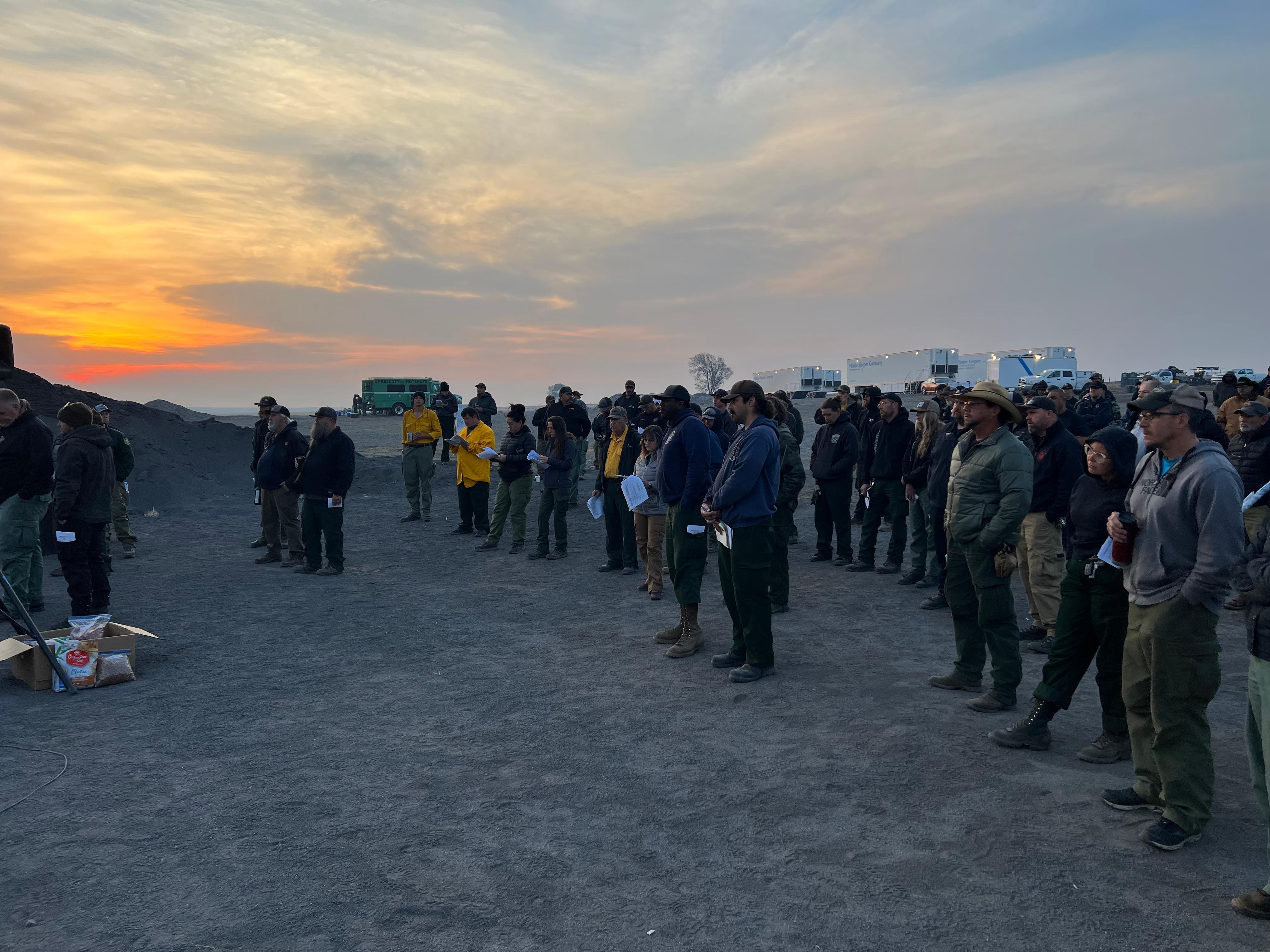 The sun comes up on Mothers’ Day, 2022 as hundreds of firefighters gather for their morning meeting at base camp near Las Vegas, NM.