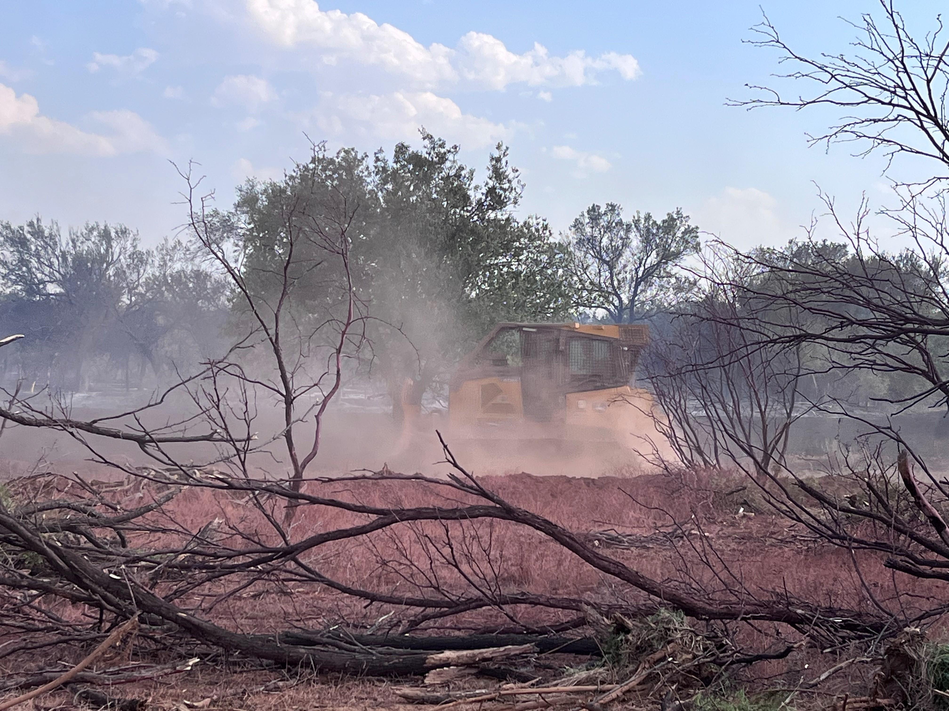 dozer is driving across clearing vegetation along the fire containment line