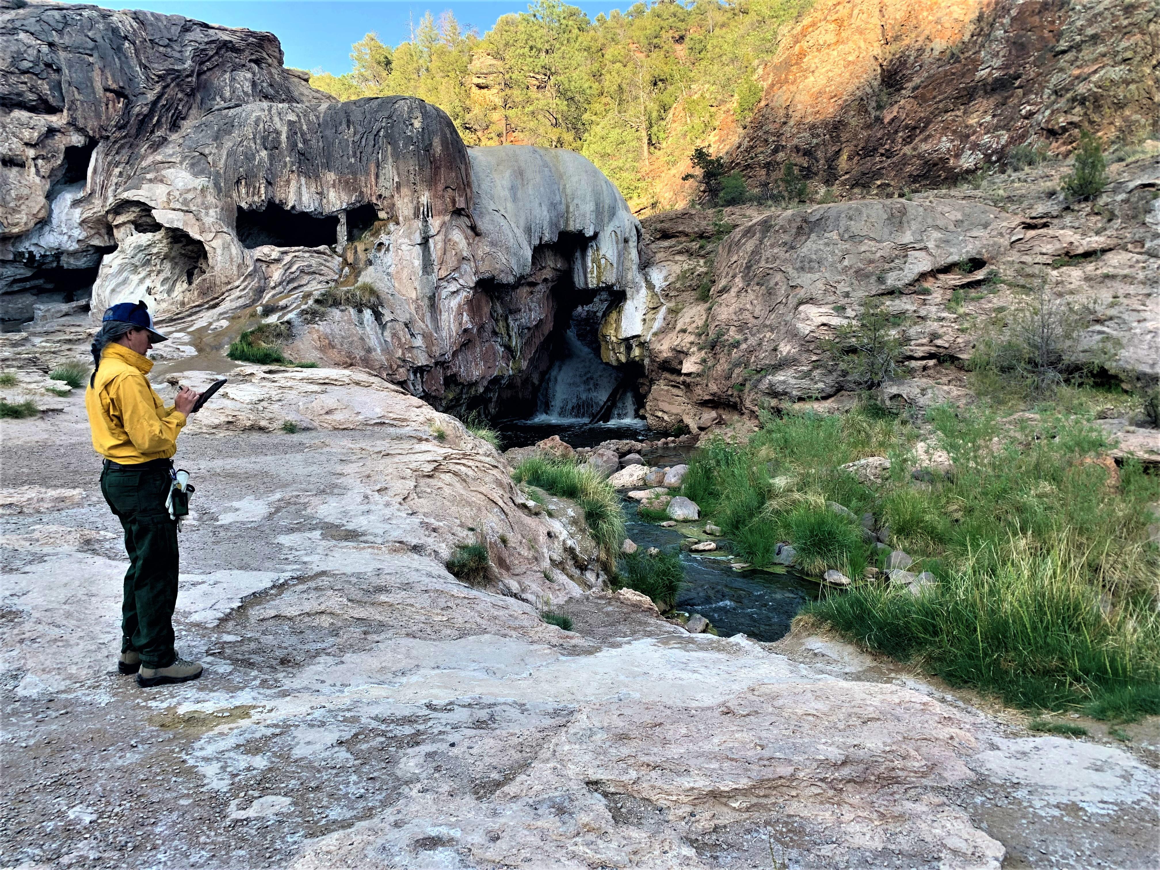 Image showing BAER Hydrologist Kelly Mott-Lacroix documenting her assessment data downstream and outside the fire perimeter of the Cerro Pelado burned area at the Soda Dam off of Highway SR4