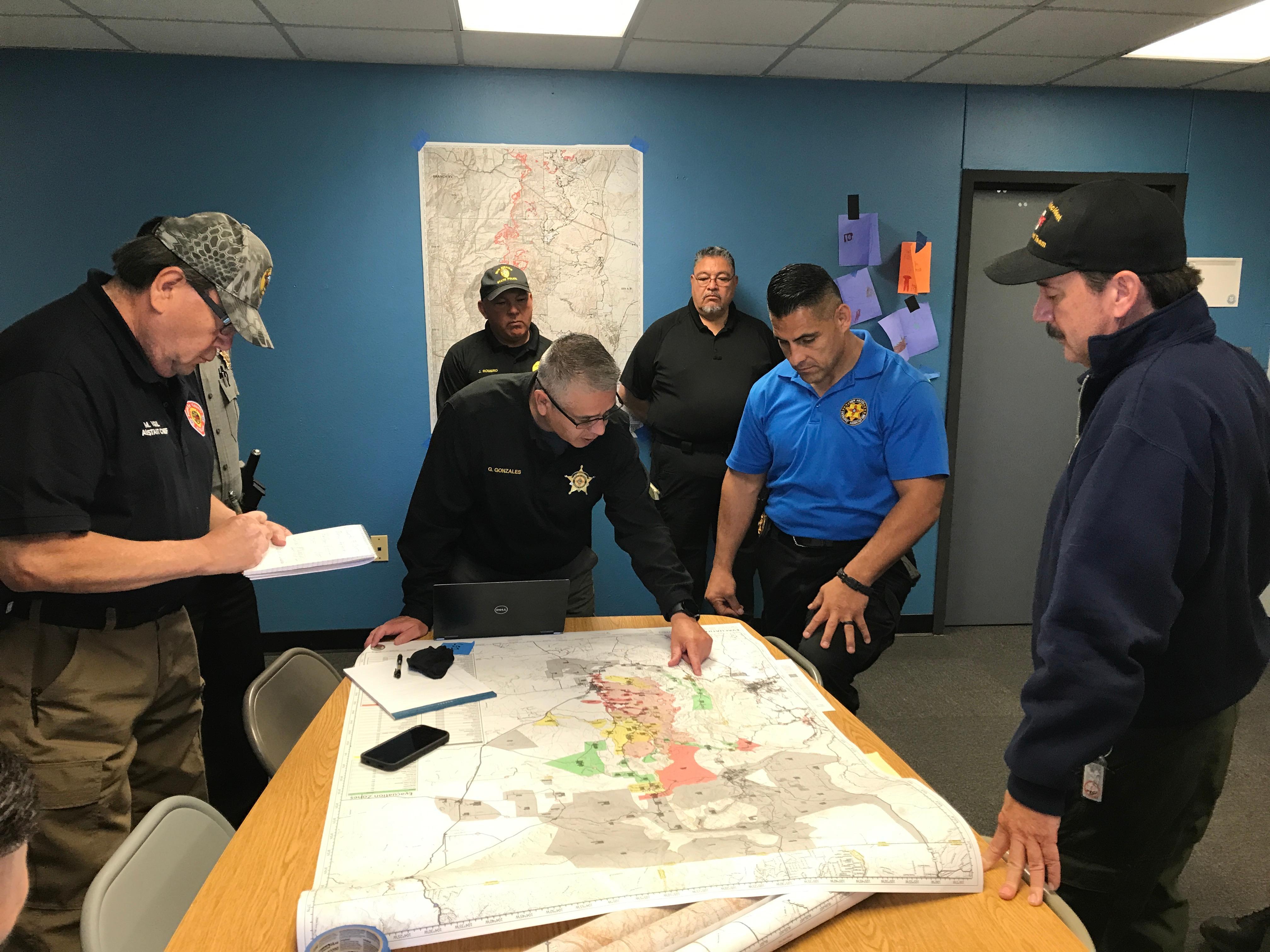 Firefighters standa around a map