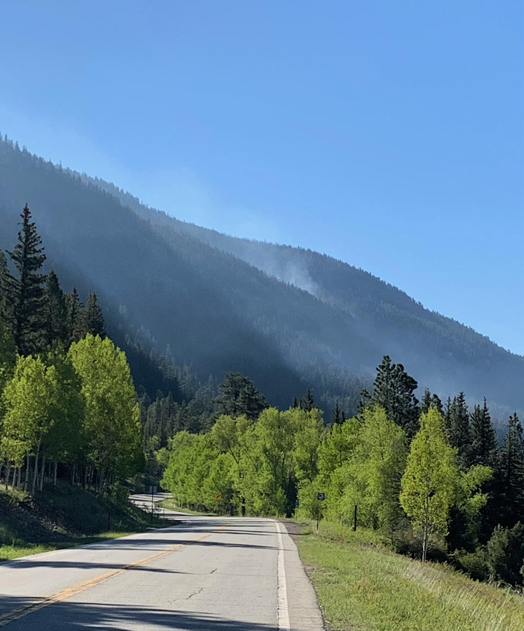 Light smoke drifts above the forest canopy on the steep slopes above highway 17.