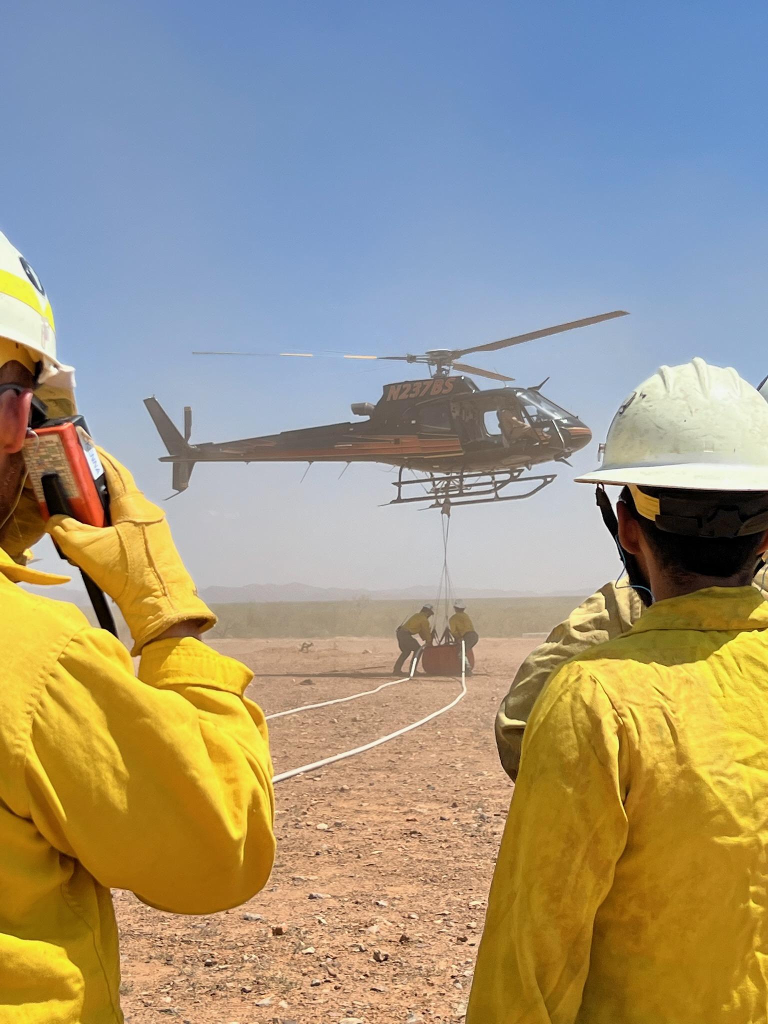 Photo showing crew communicating over radio near helicopter