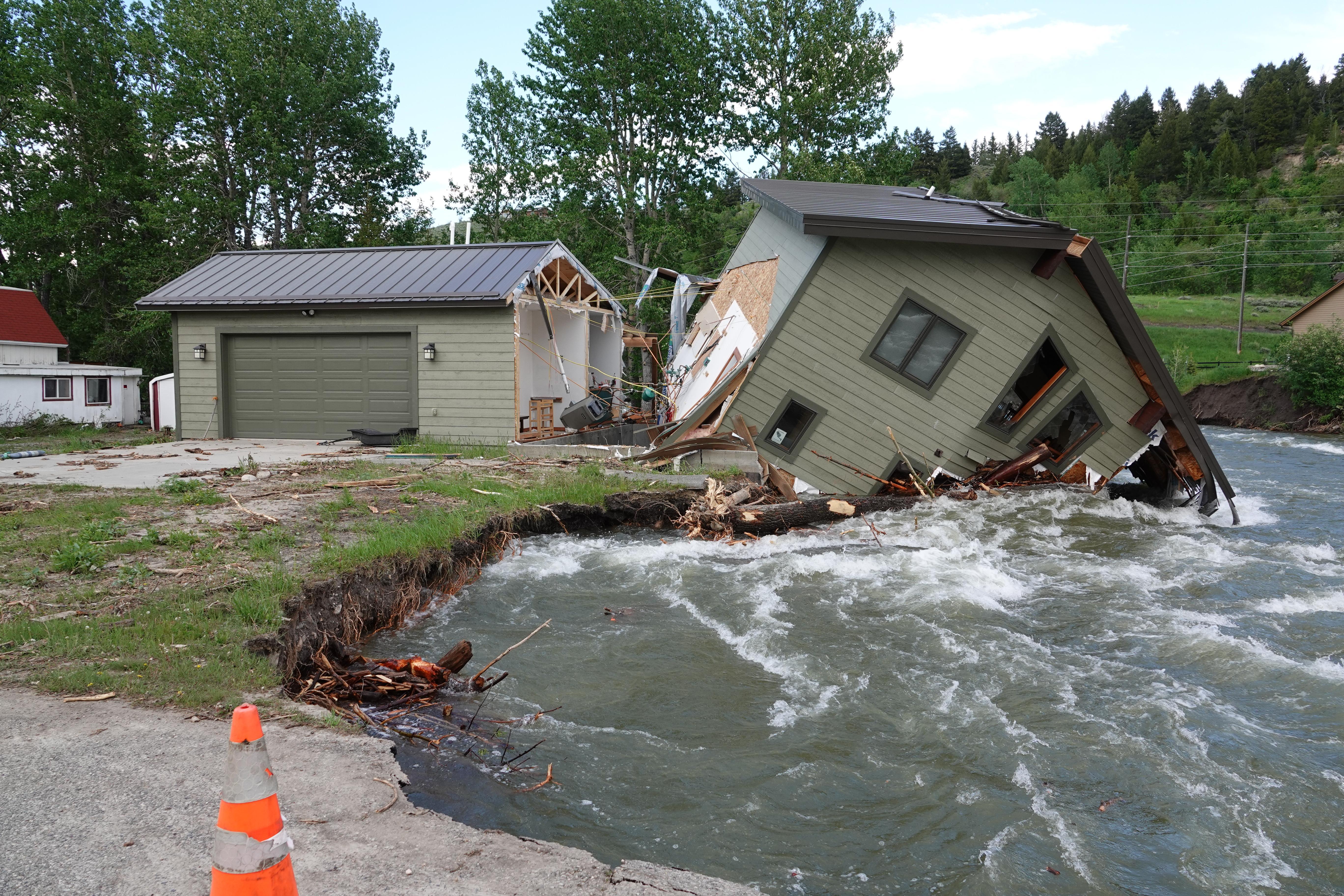 Image of damaged home partially submerged in rapidly flowing creek