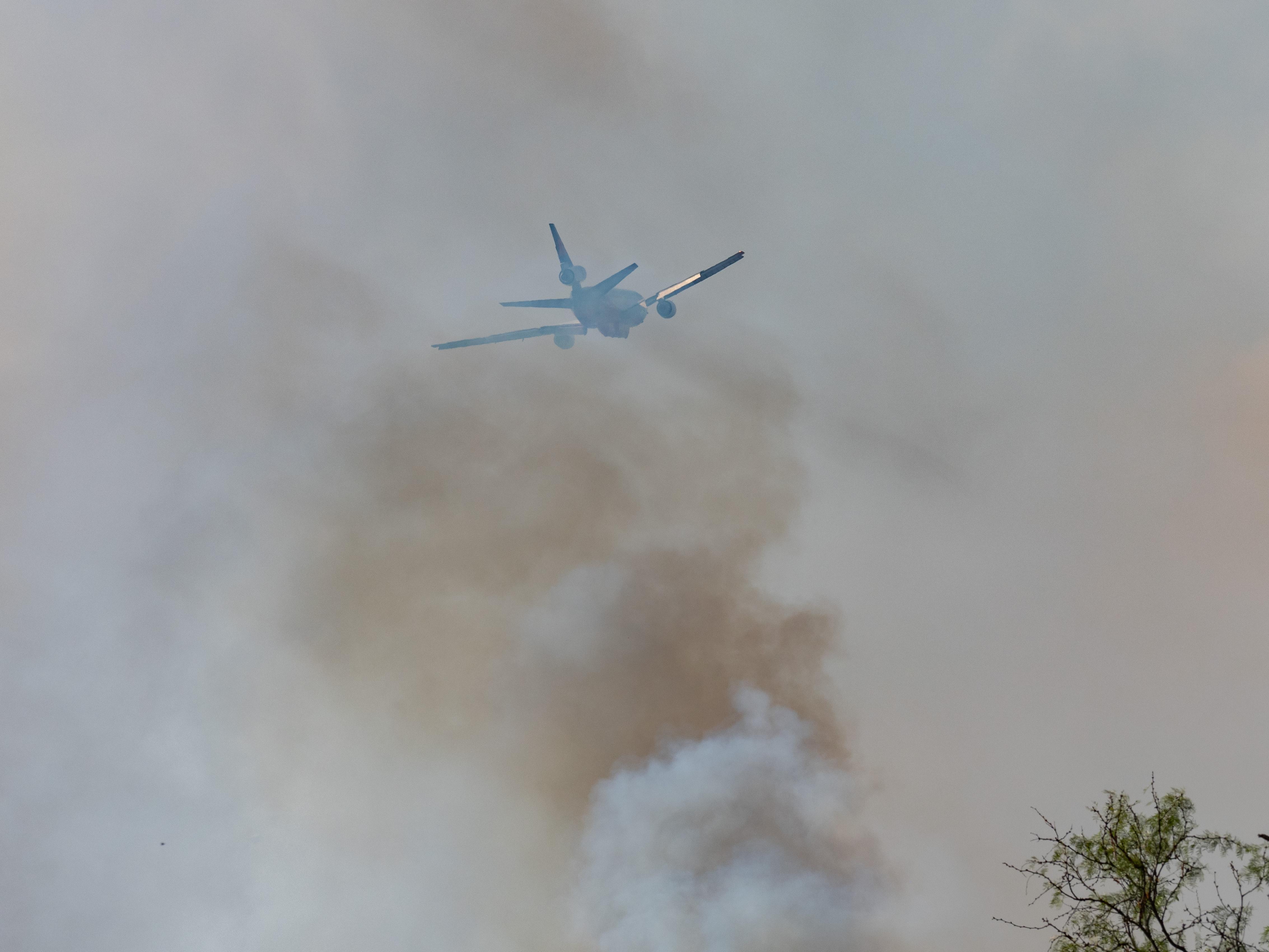 A DC10 airtanker flies near the smoke plume from the fire