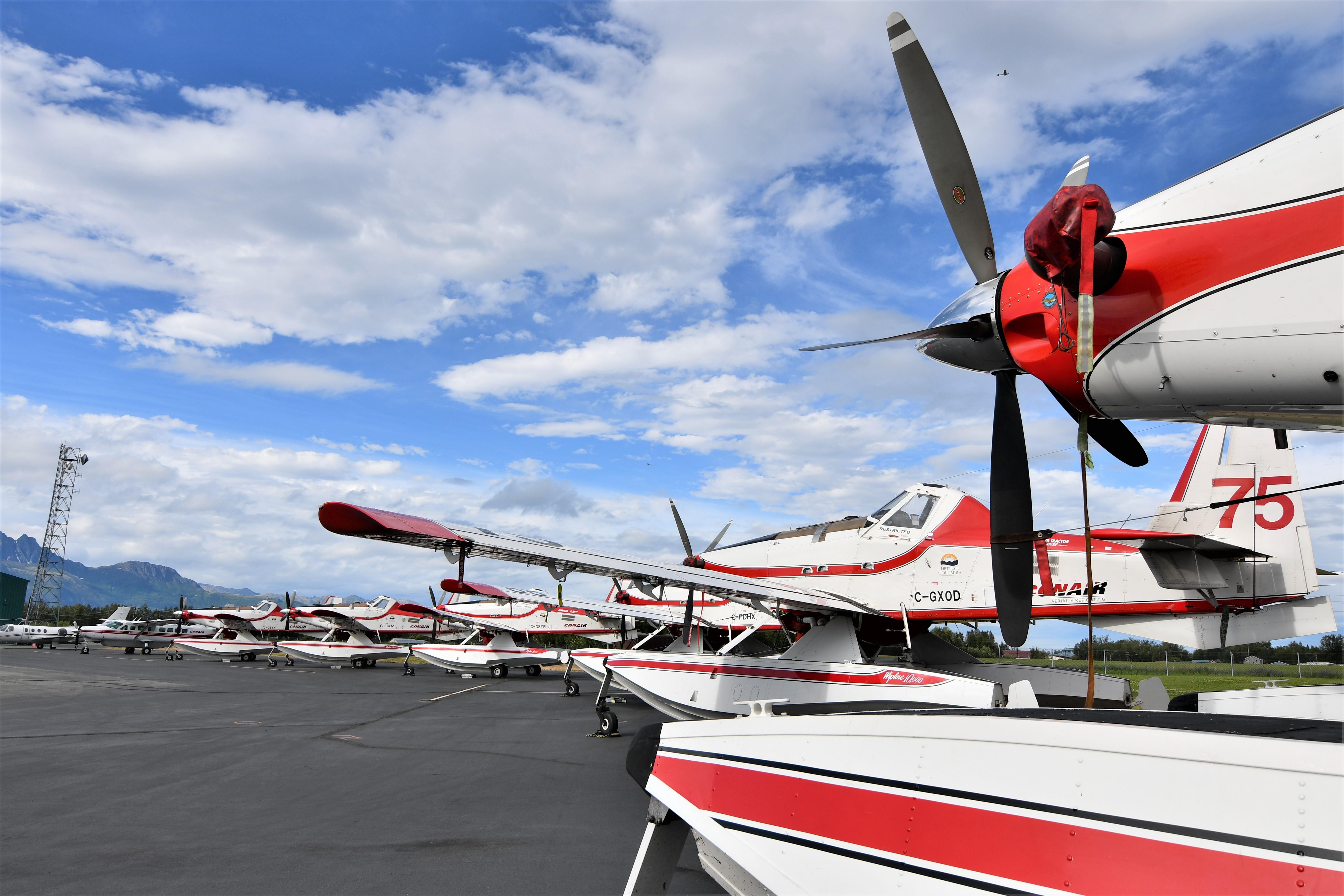 Several Fire Boss airplanes are parked on the pavement at the Palmer airport.