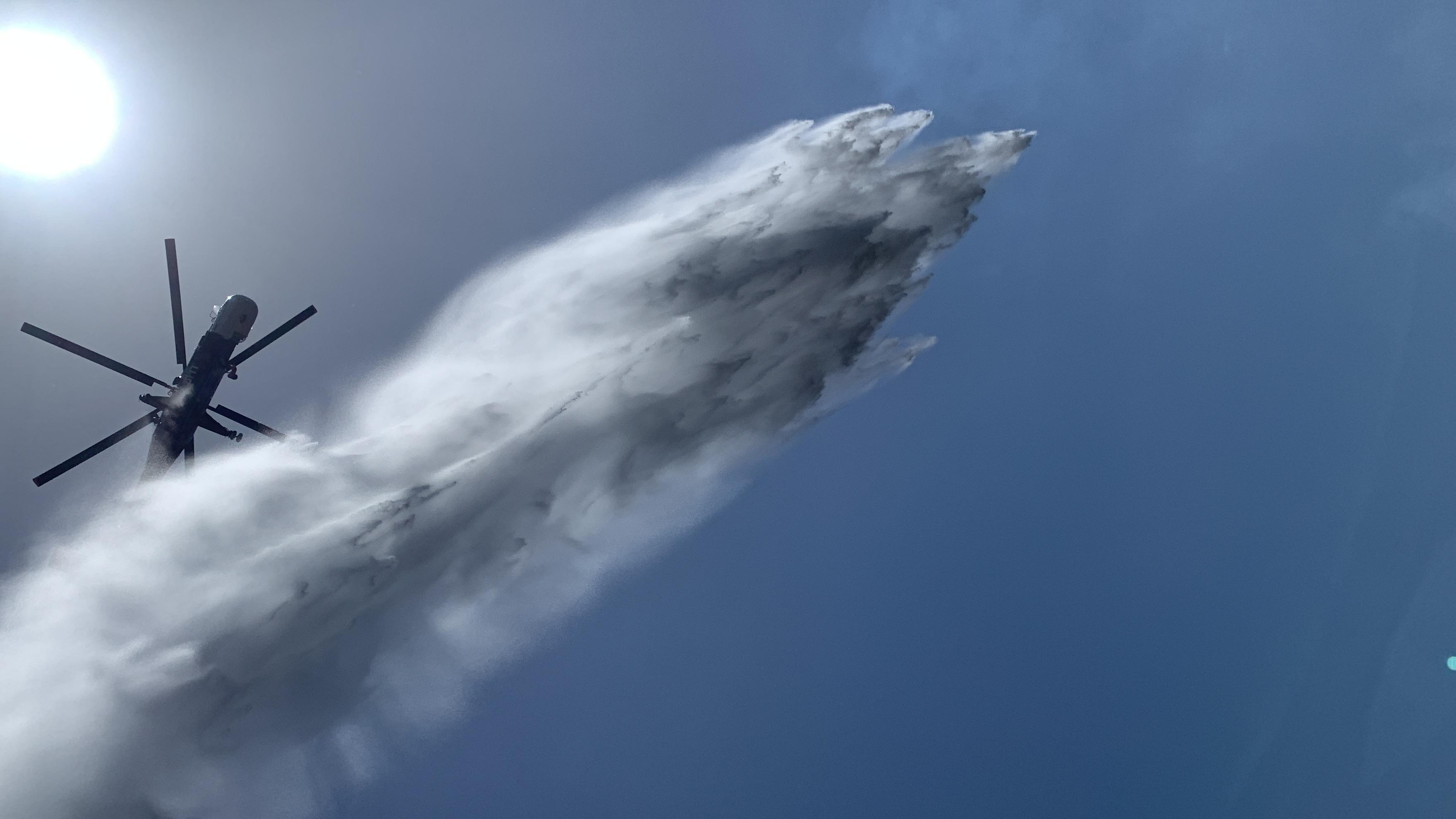 view of a helicopter water drop from dozer operator's perspective