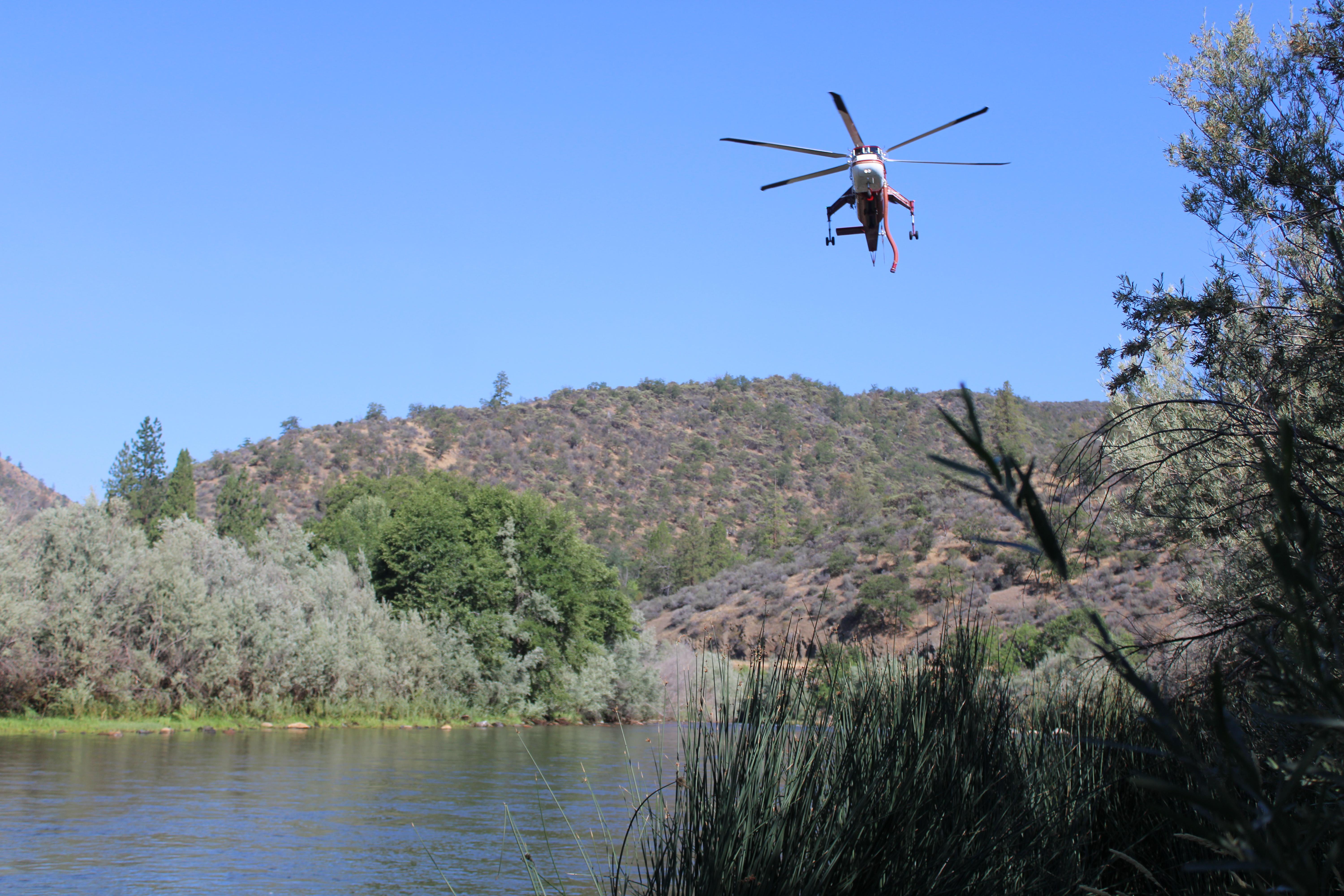 Helicopter transport Service helicopter 6HT dipping snorkel in Klamath River to fill with water 