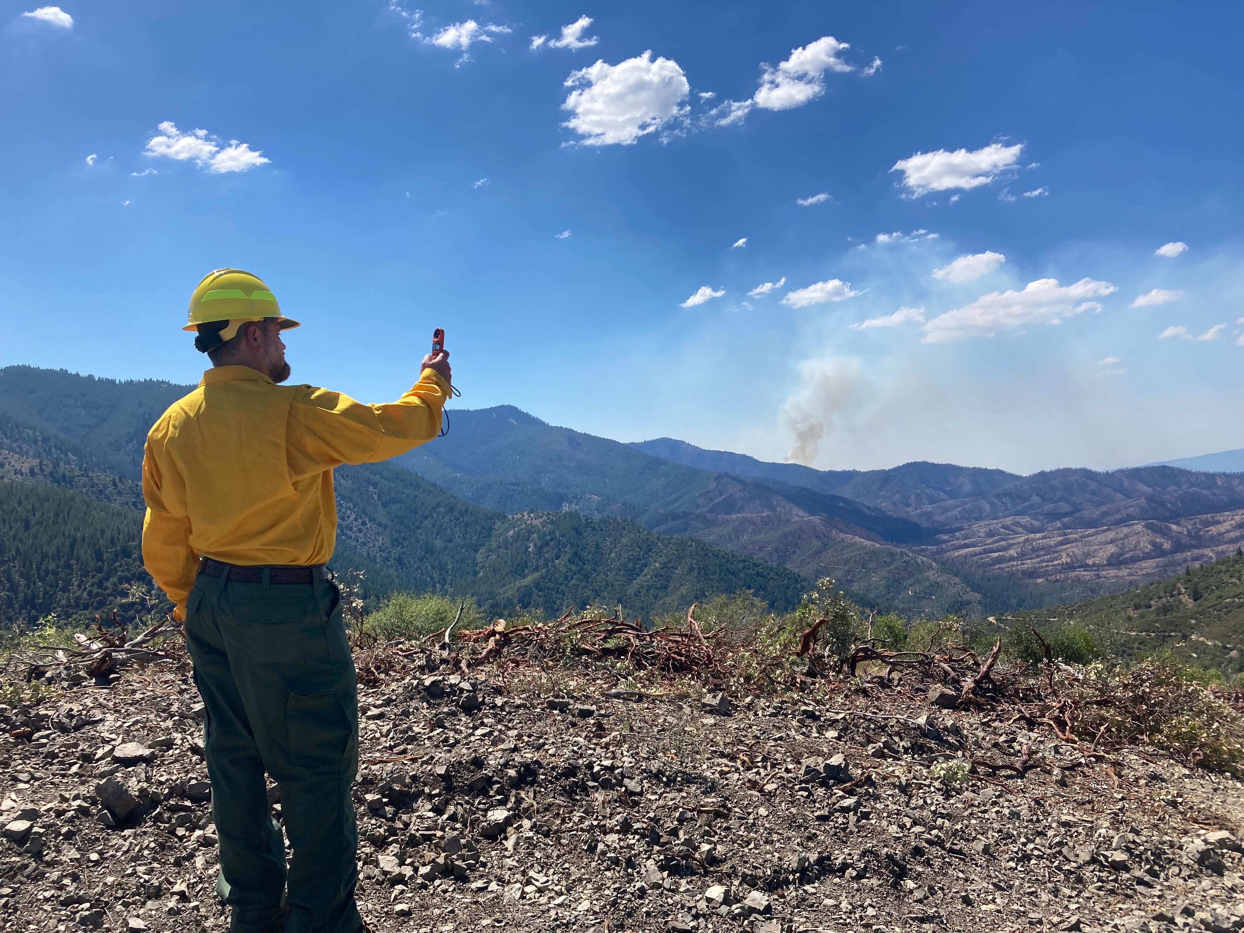 Incident meteorologist checks wind speed on a ridge outside the fire perimeter