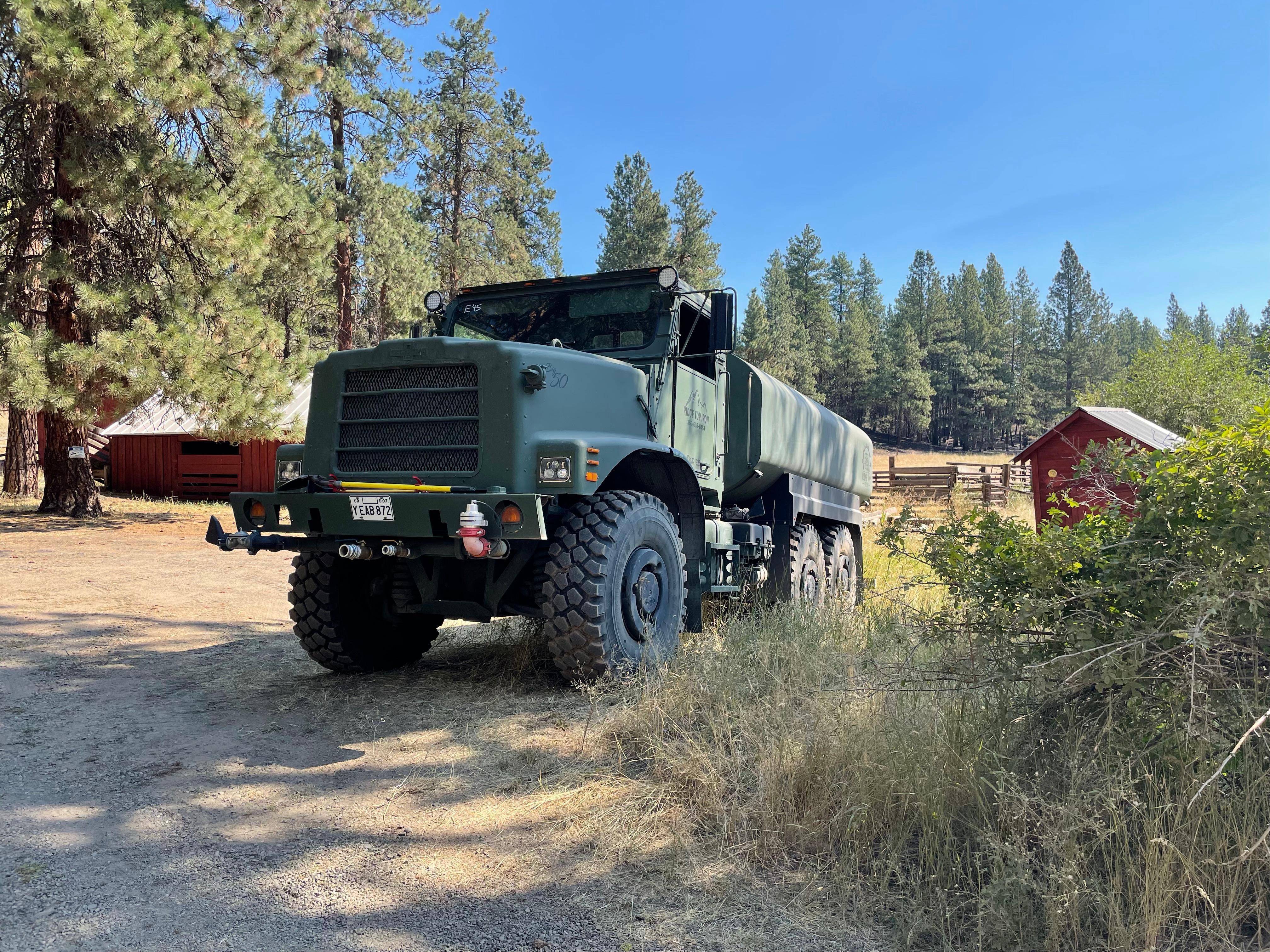 A green water tender is parked on the Cow Canyon fire.