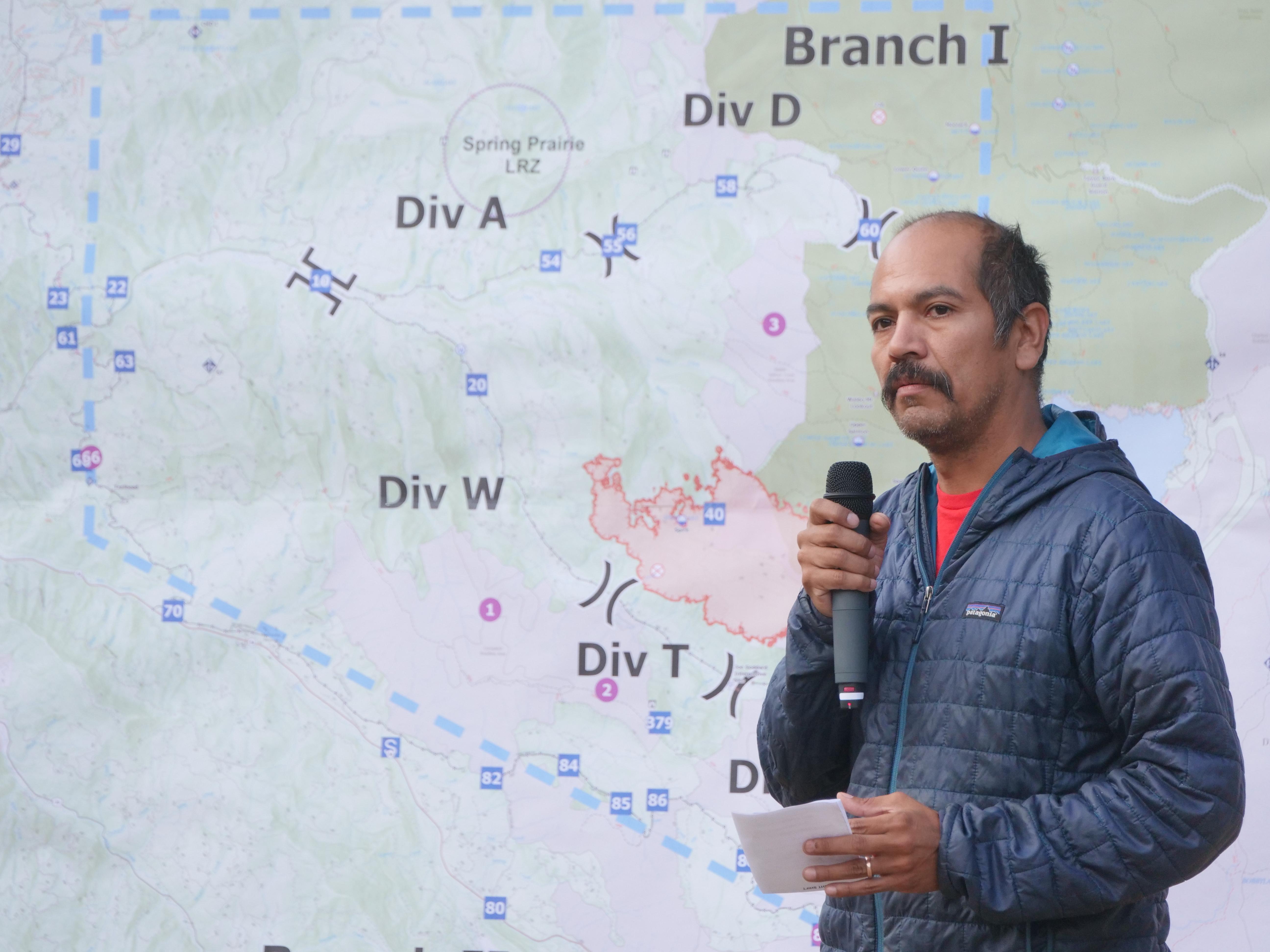 A man who works as a fire behavior analyst is talking in front of a map of the Cedar Creek Fire.