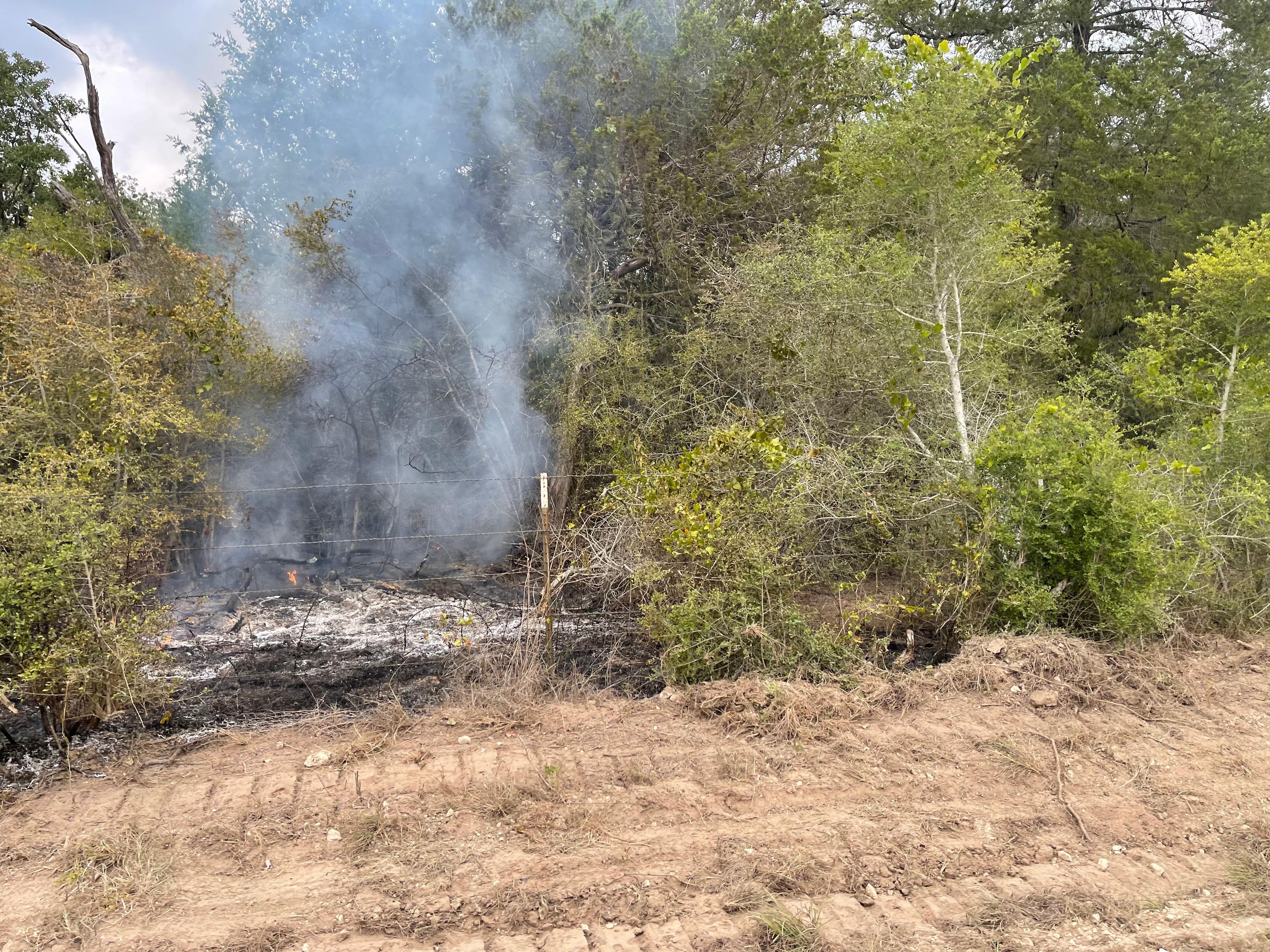 Smoke showing from vegetation that is still holding heat along the roadside