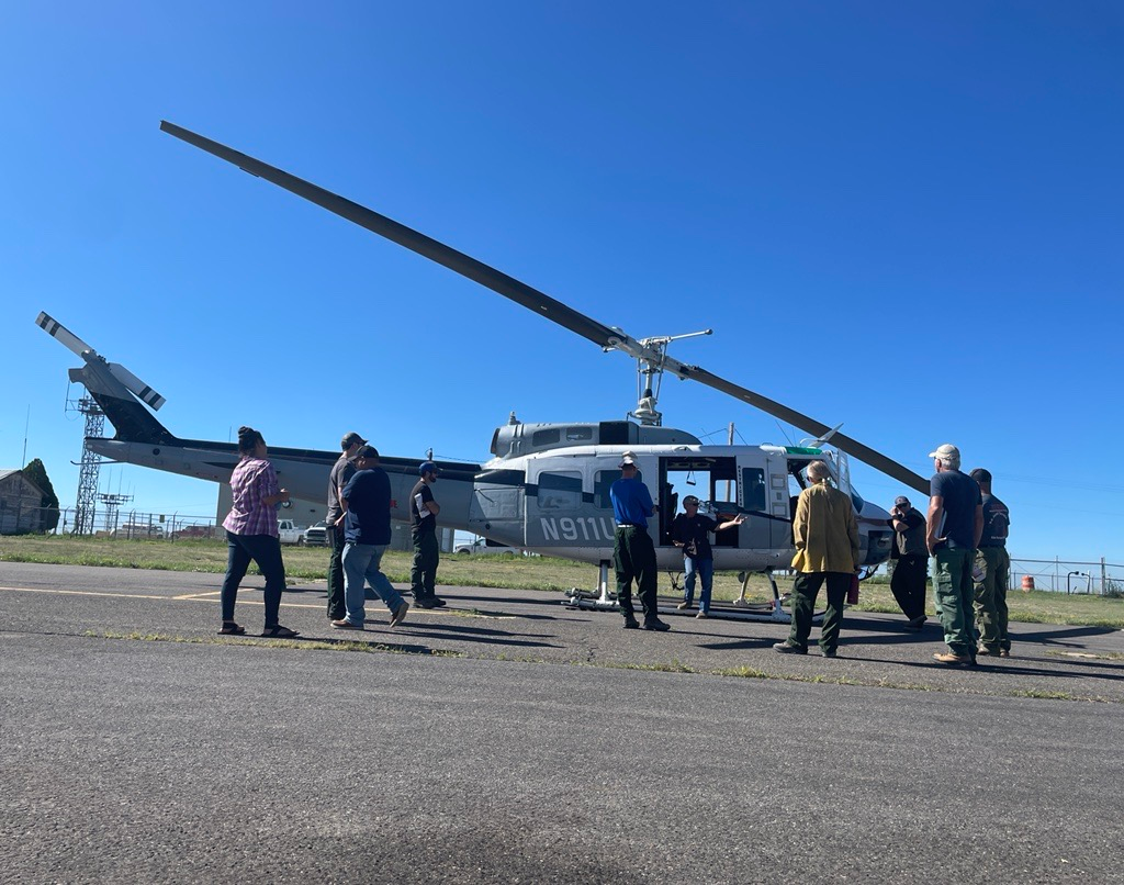 Image of the BAER Team standing in front of a helicopter during a safety briefing with the helicopter pilot. 
