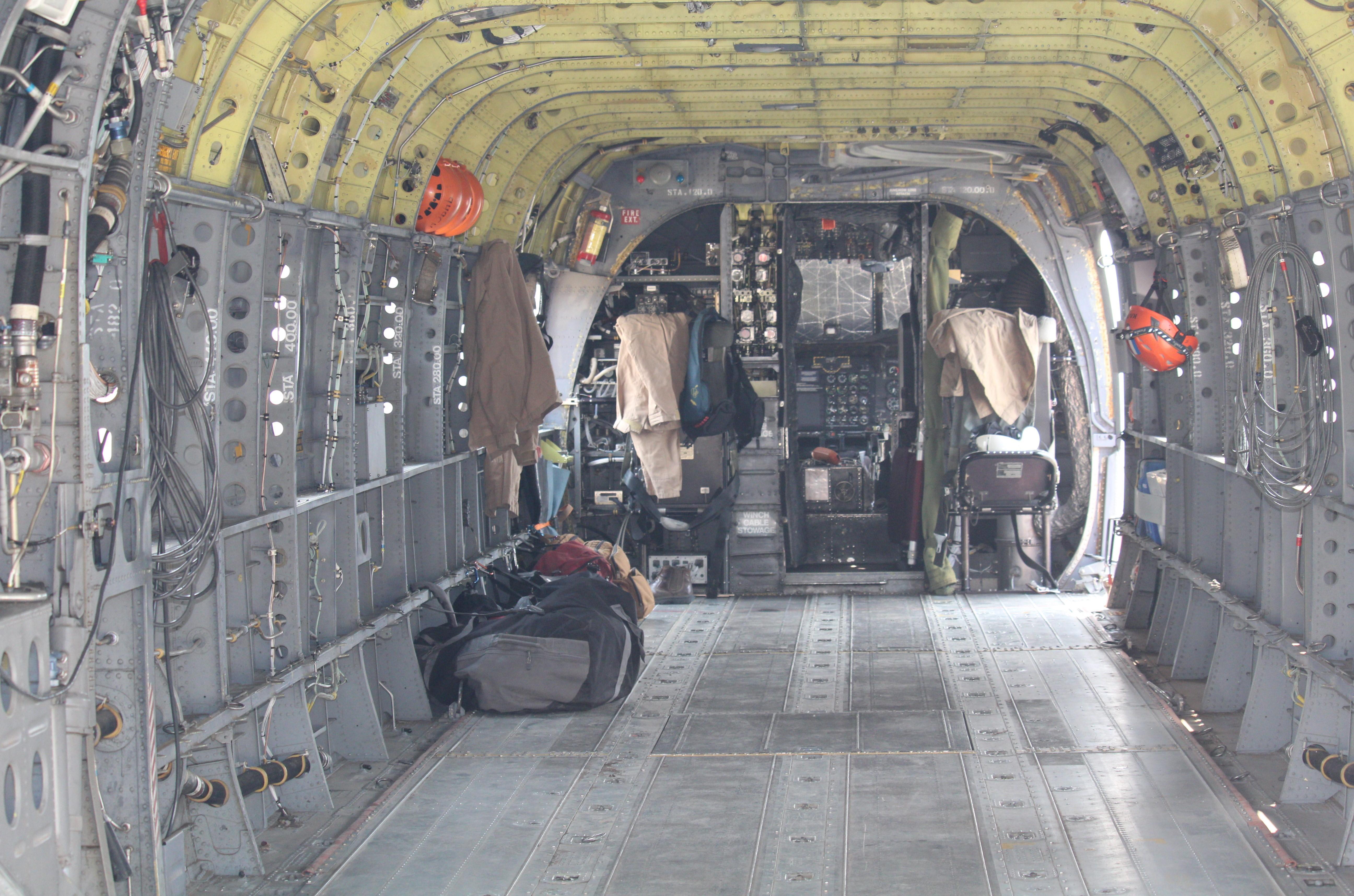 Inside the cockpit of a helicopter, two seats surrounded by wires, gages and metal supports
