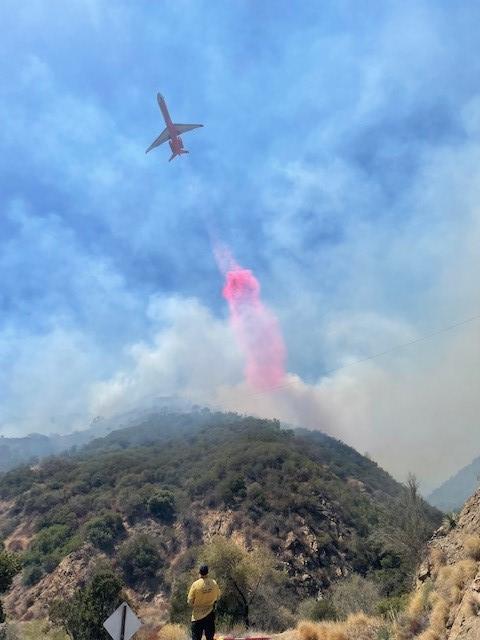 Plane has dropped red substance (retardant) over mountains to help put the fire out.