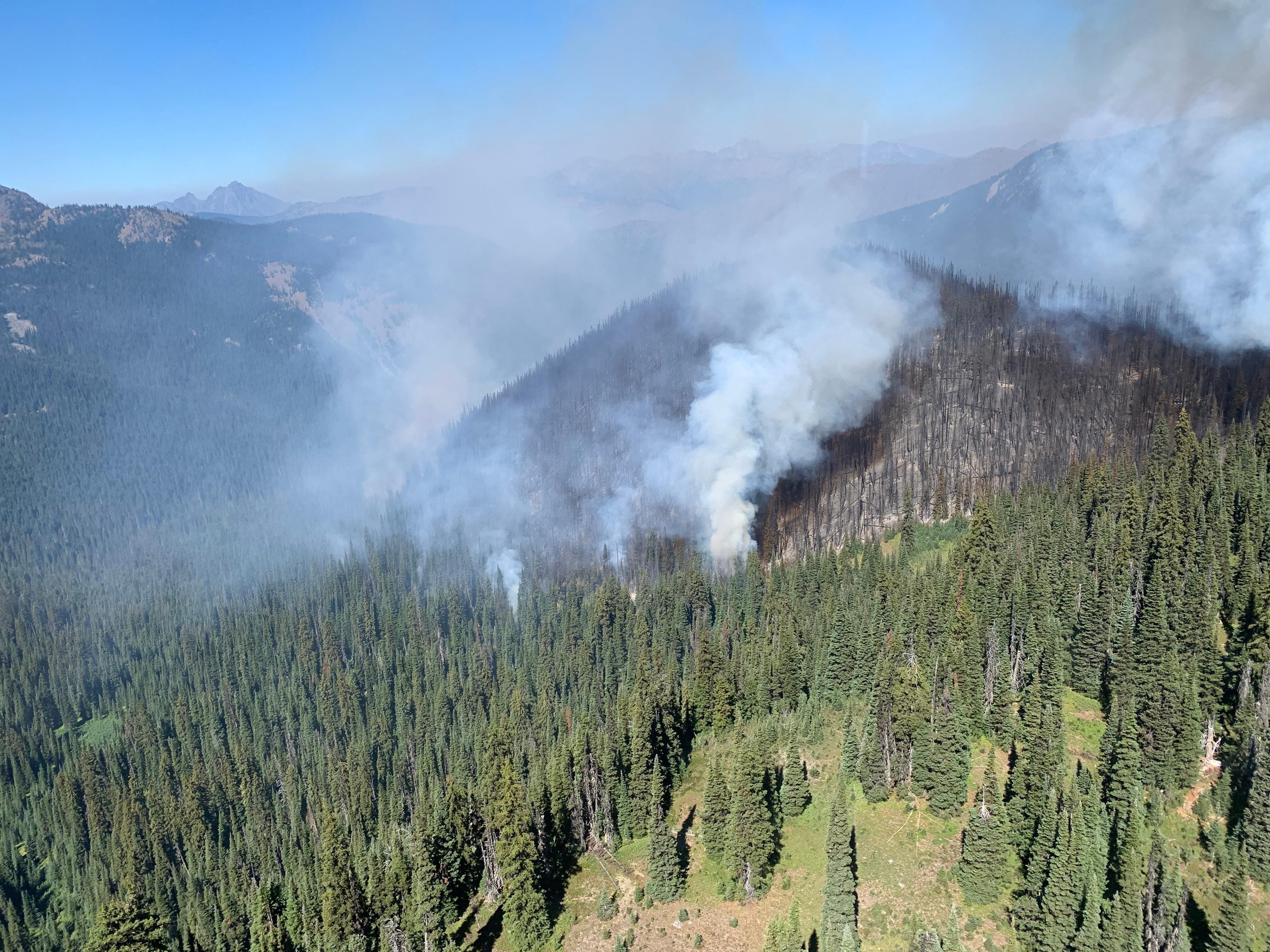 A  small column of smoke rising off of steep wilderness topography