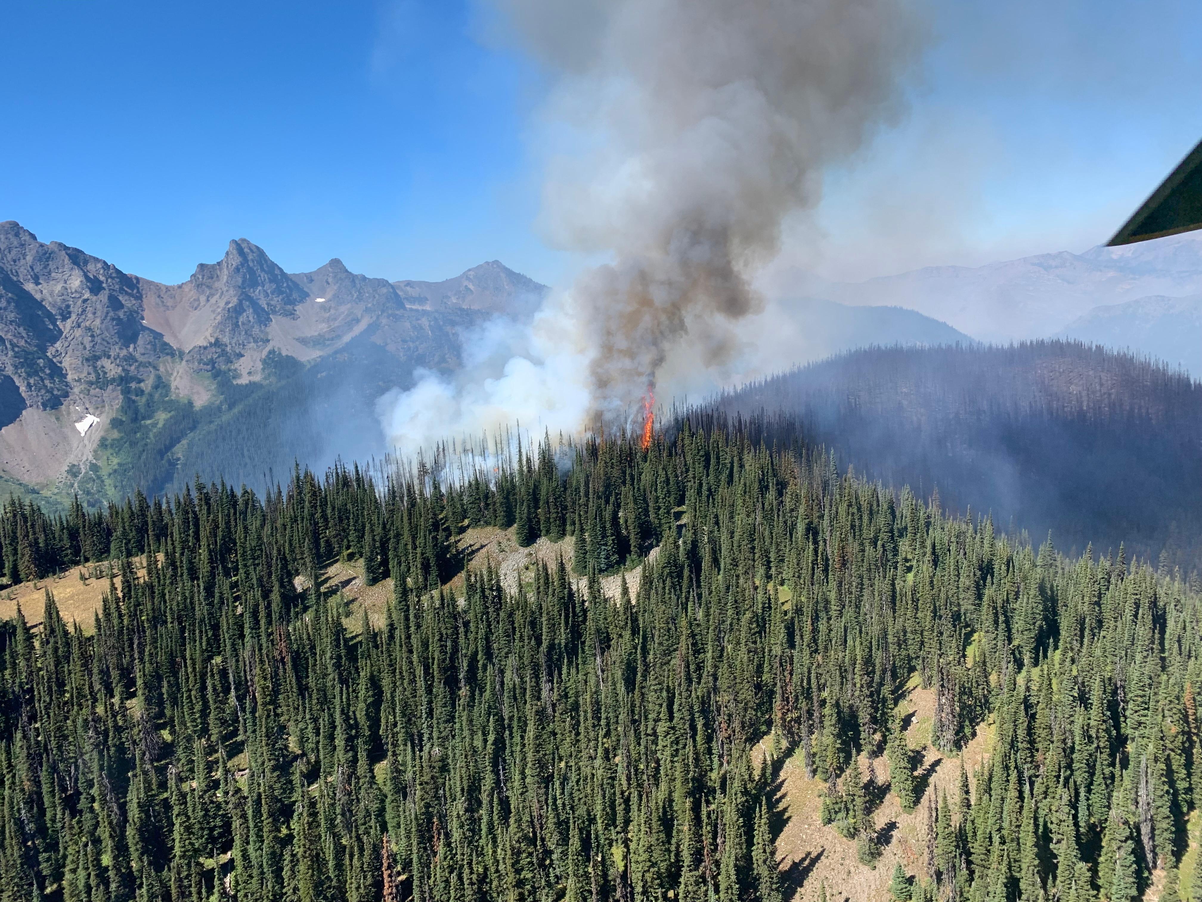 A  small column of smoke rising off of steep wilderness topography