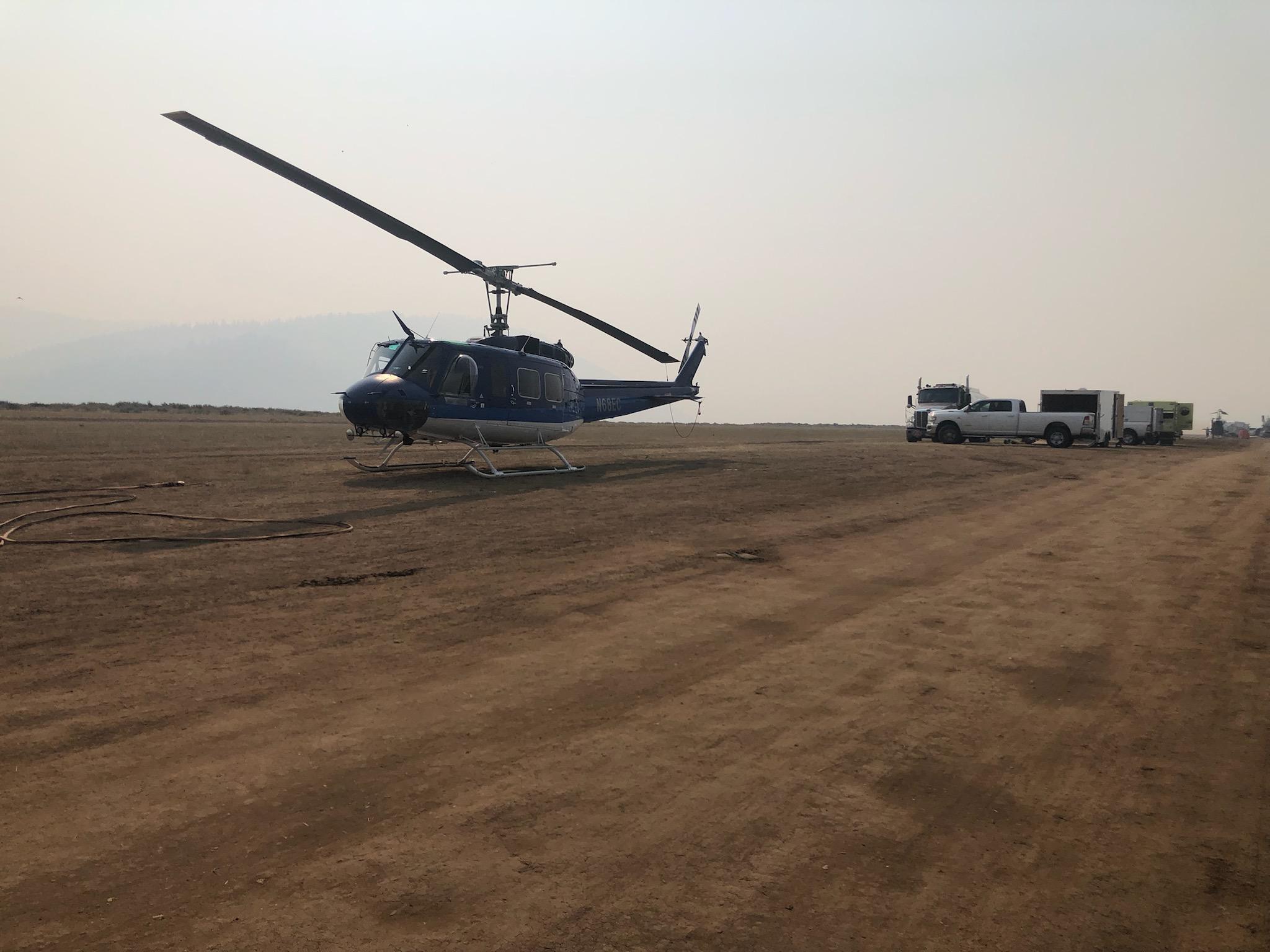 A helicopter on the ground in smoke at Stanley Helicopter Base