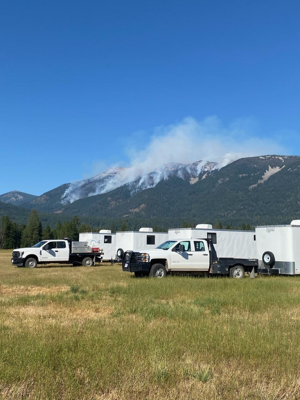 Smoke from the Billiard Fire on the hillside with trucks in the foreground as seen from the Incident Command Post for the Bull Gin Complex on September 4, 2022.