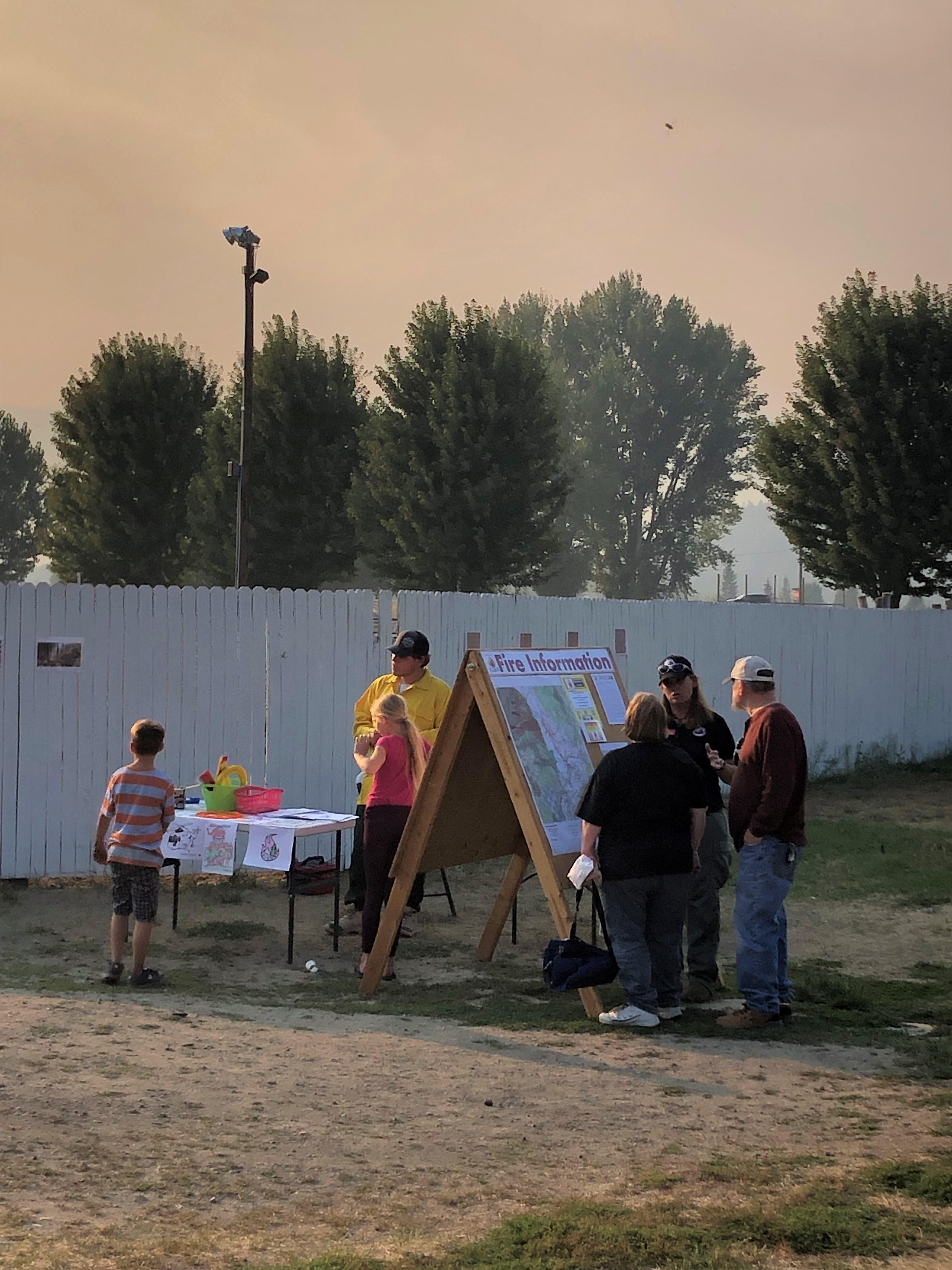 Fire Information at the Bonners Bash Demo Derby. Folks attending Derby could get information on the fire, along with kids activities. Two Fire Information Officers talking to folks at Information Board.