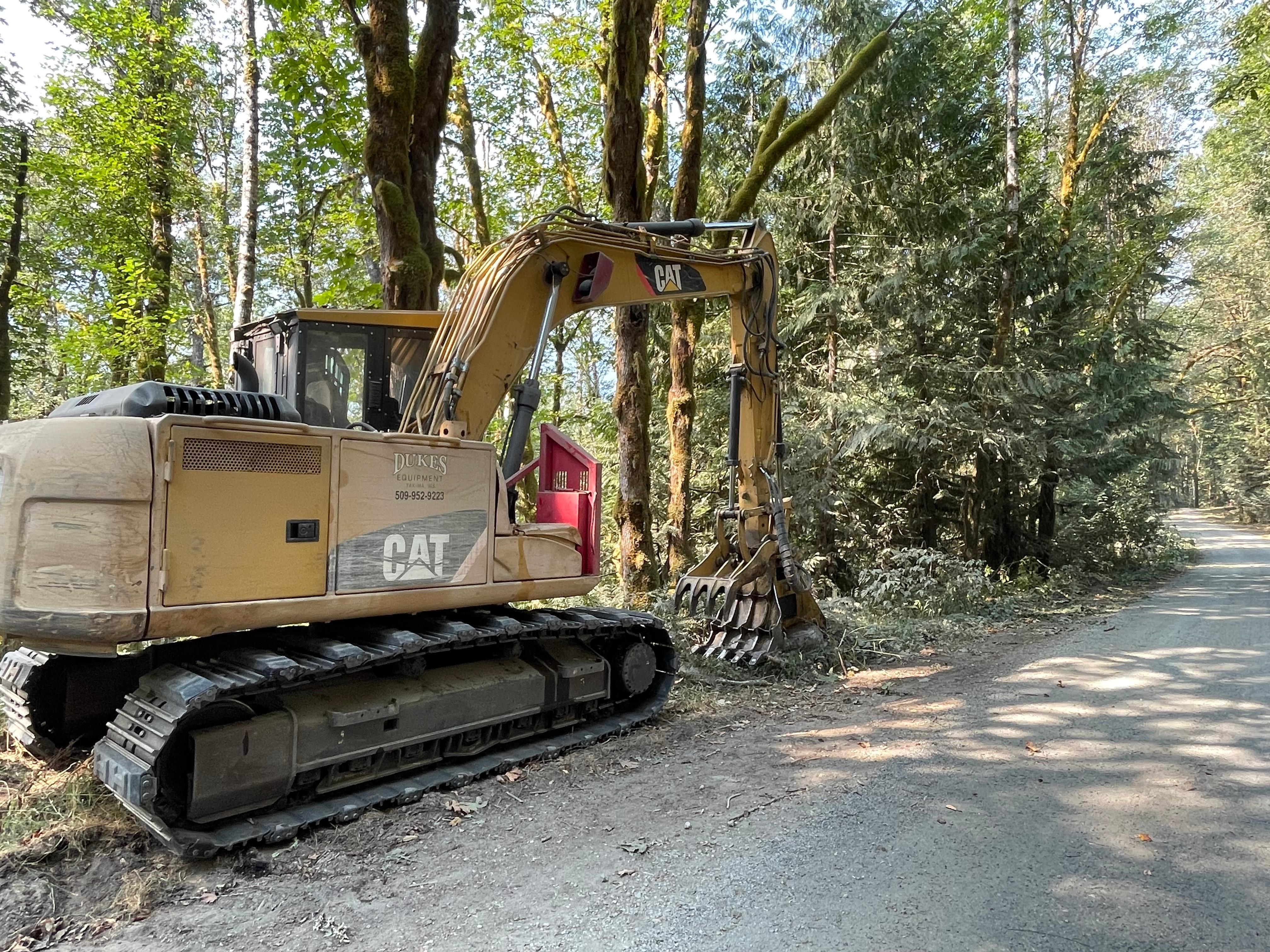 An excavator mounted masticator clearing brush along Suiattle River Road