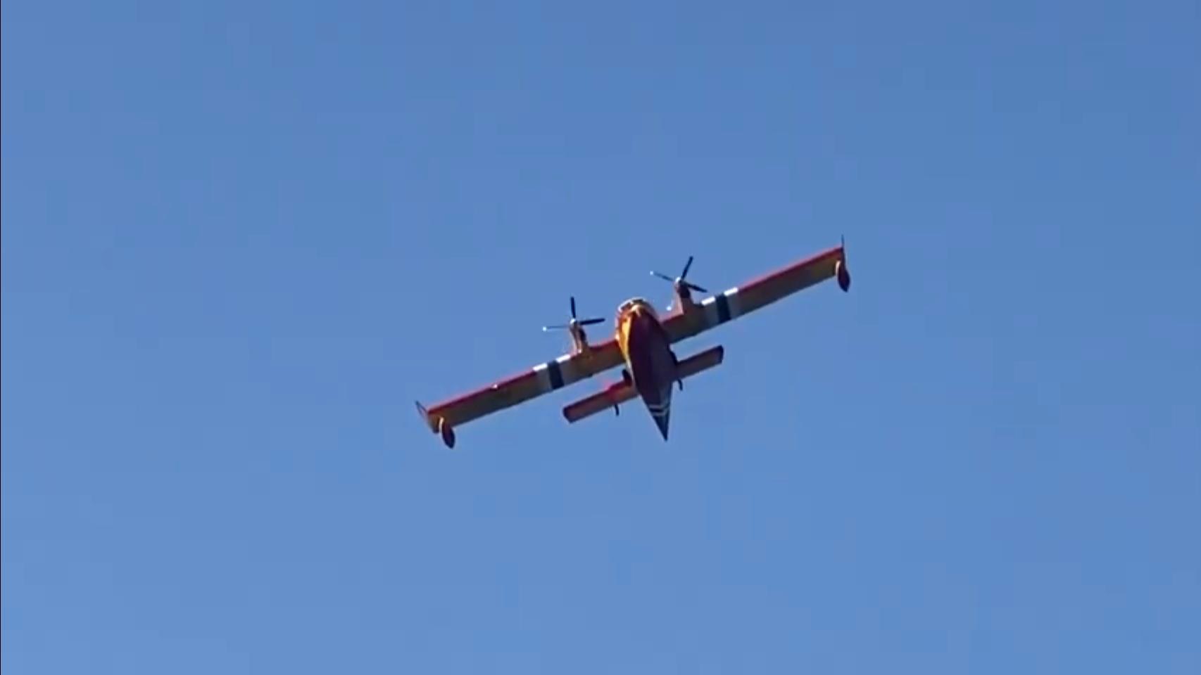 A large yellow airplane is flying through a blue sky