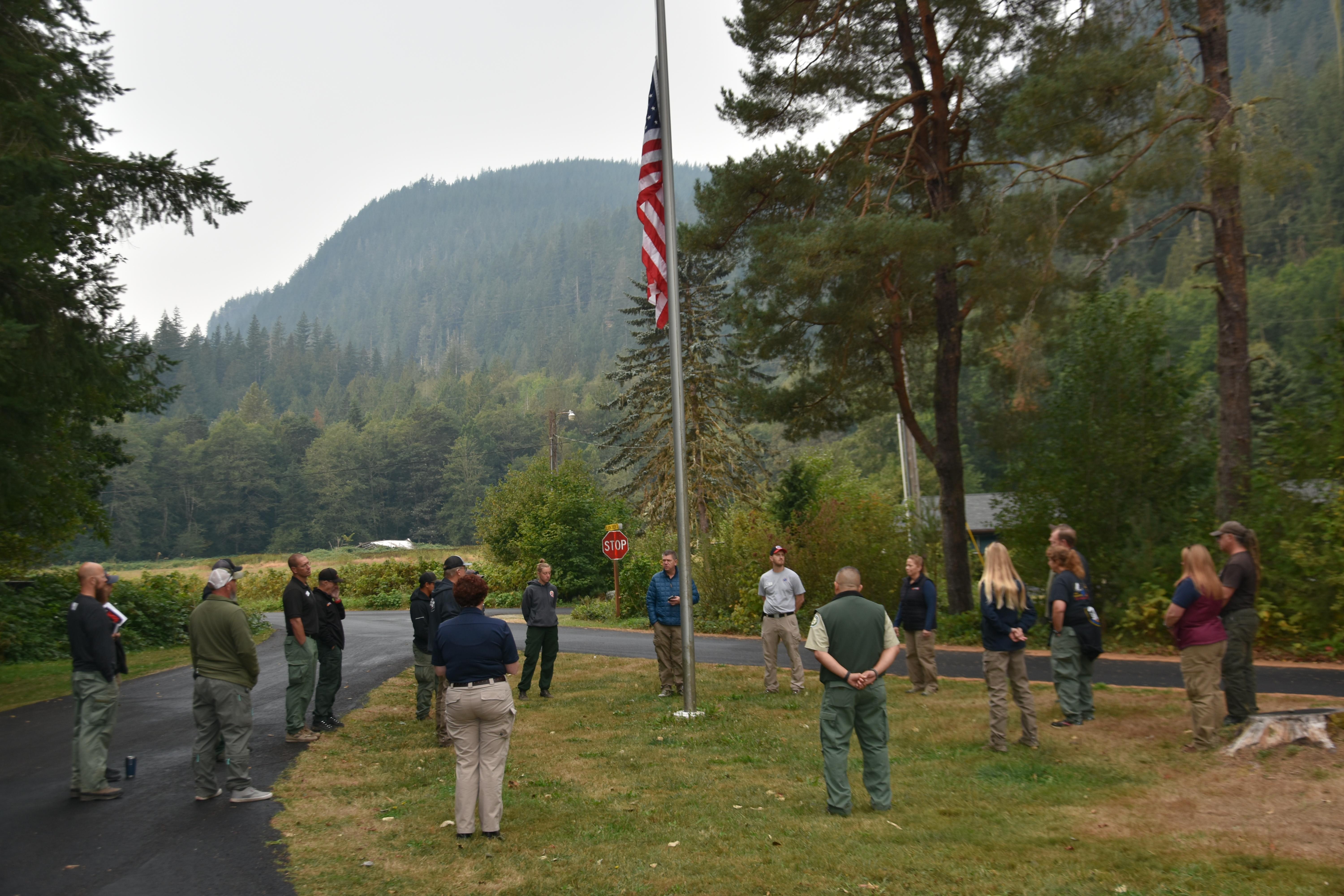 A group of people standing in reverence around a flagpole.