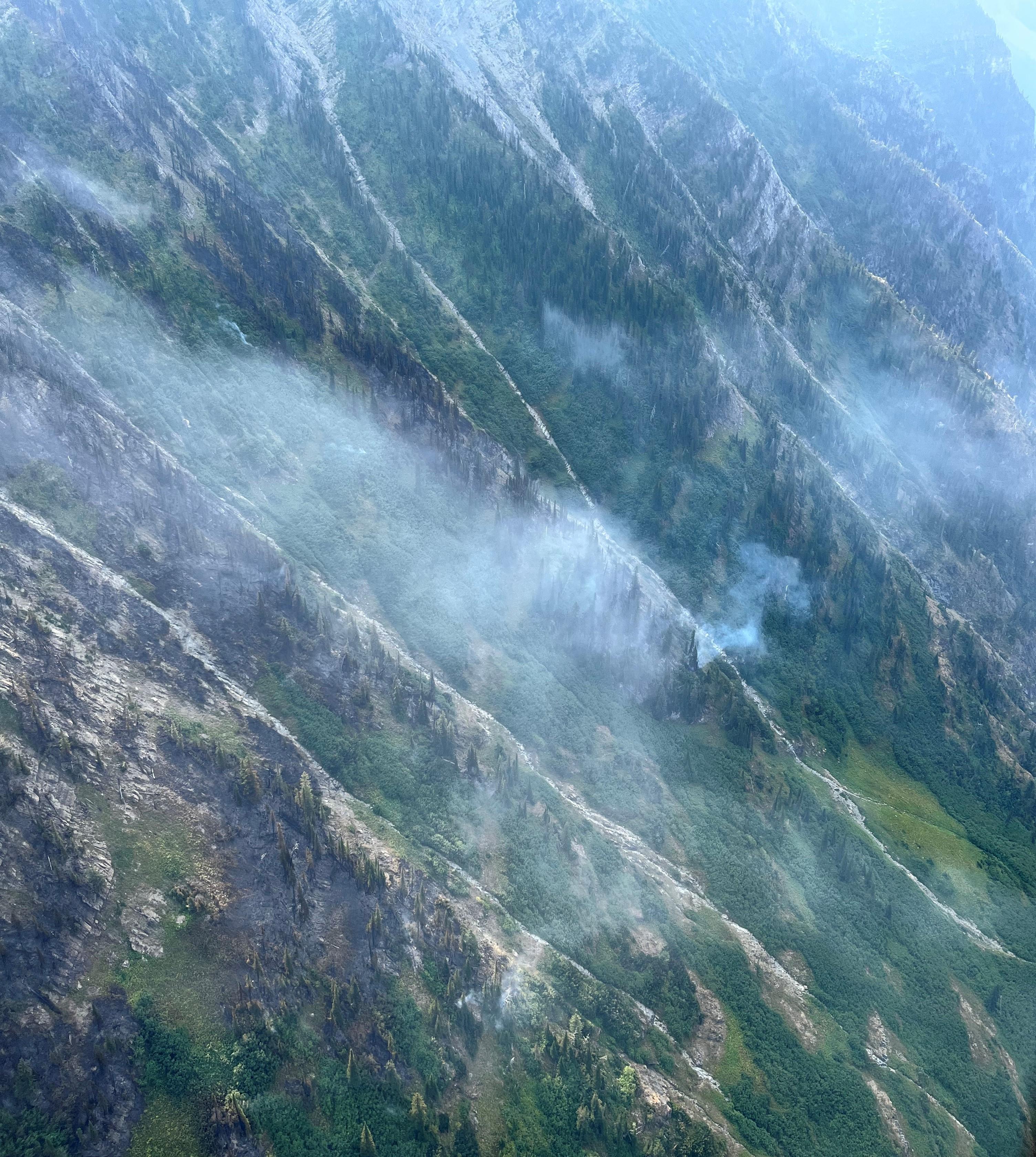 Aerial view of a patchwork of burned area on steep slopes.