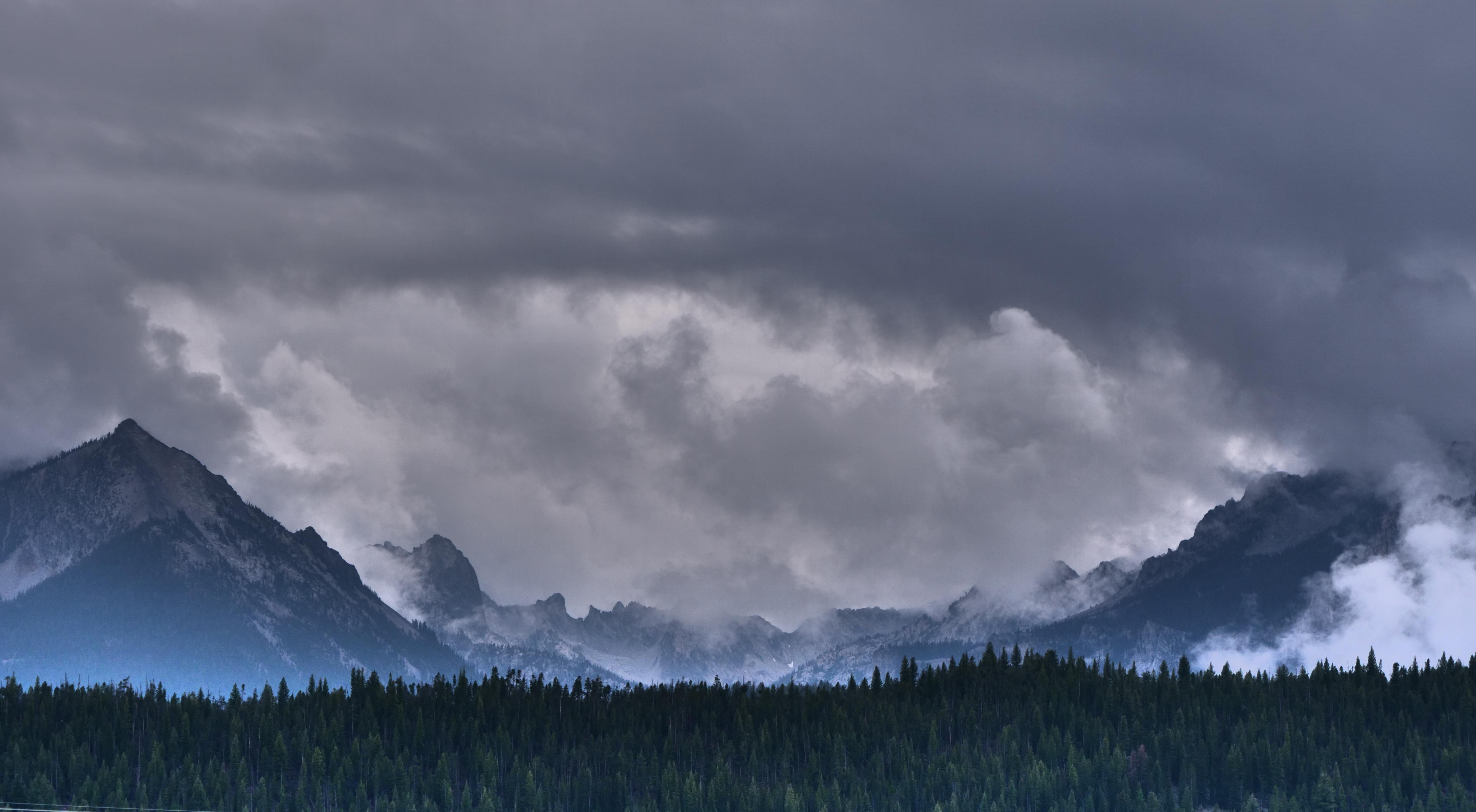 Rugged mountains are seen, with clouds and mist swirling around the peaks.