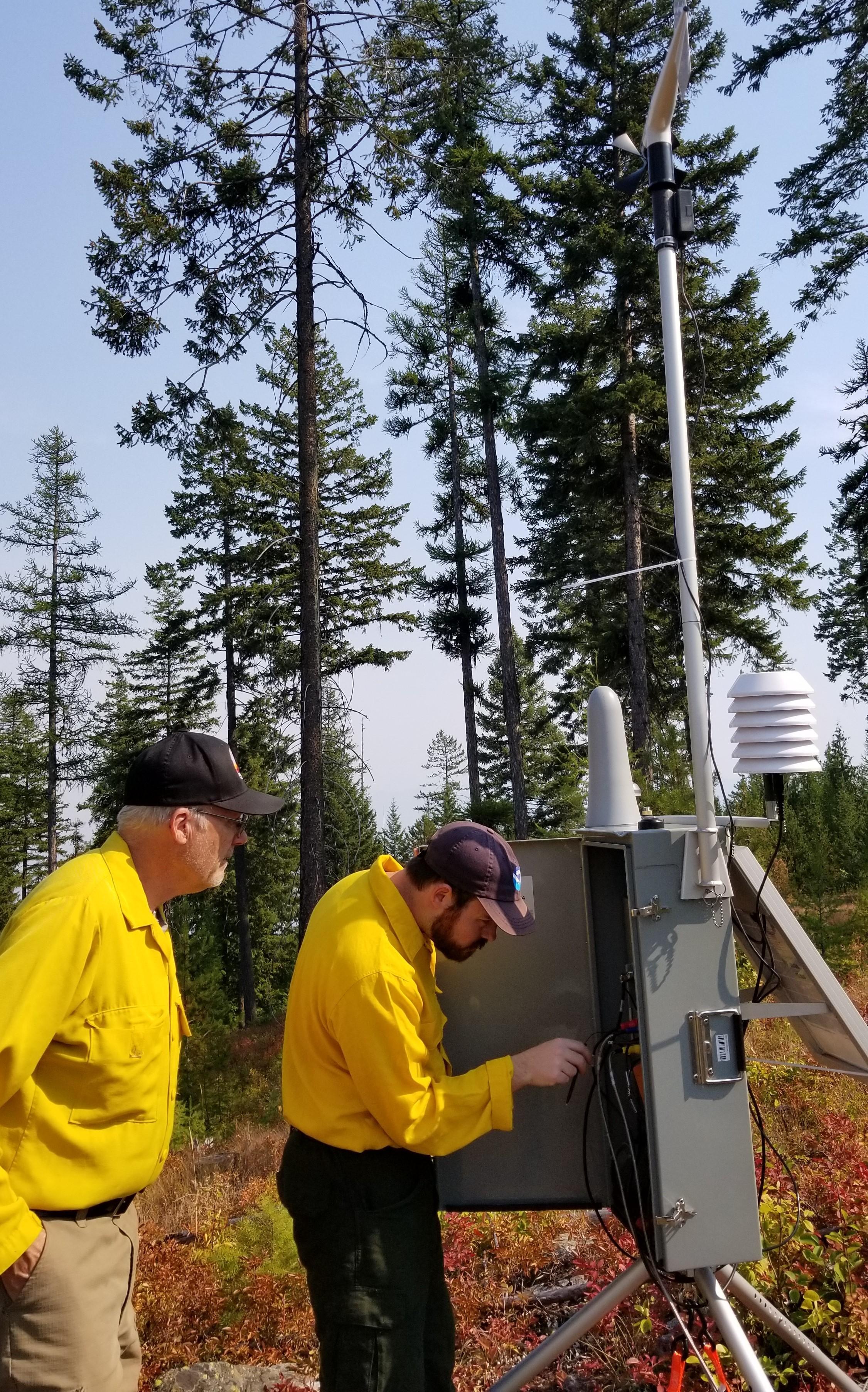 Meteorologist and Fire Behavior Analyst setting up a remote weather station in the field .