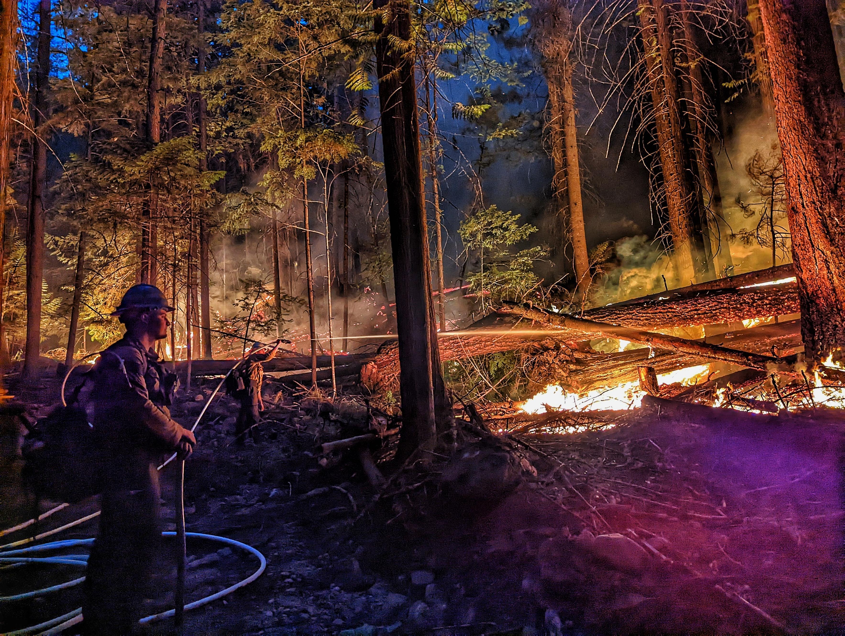 Night shift holding the line Sept. 13. Two firefighters cooling off a section of line with hose and water.