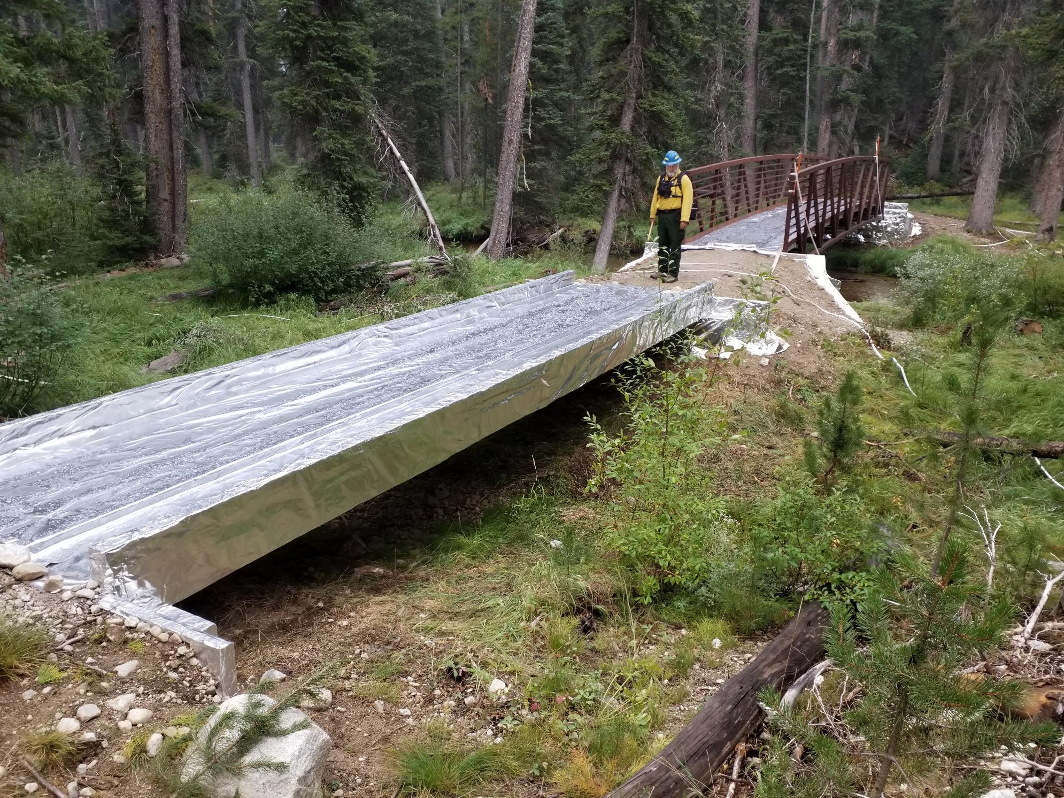 Forest Engineer inspects protection measures on a bridge at  Alpine Creek, located on the trail network above the Alturas lake trailhead.
