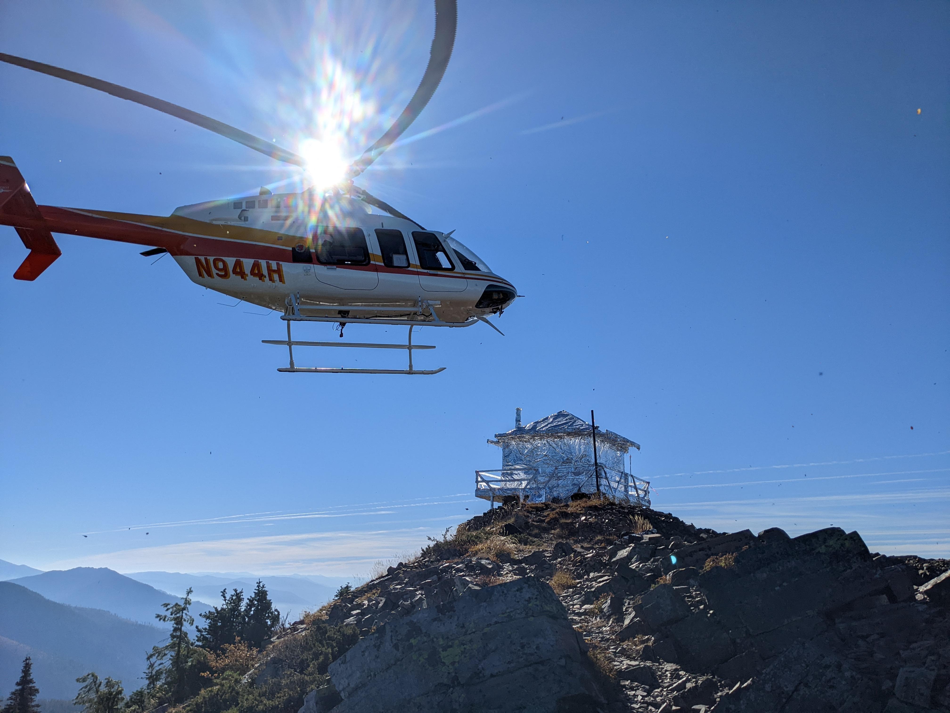 Helicopter approaching Star Peak Lookout, which is wrapped