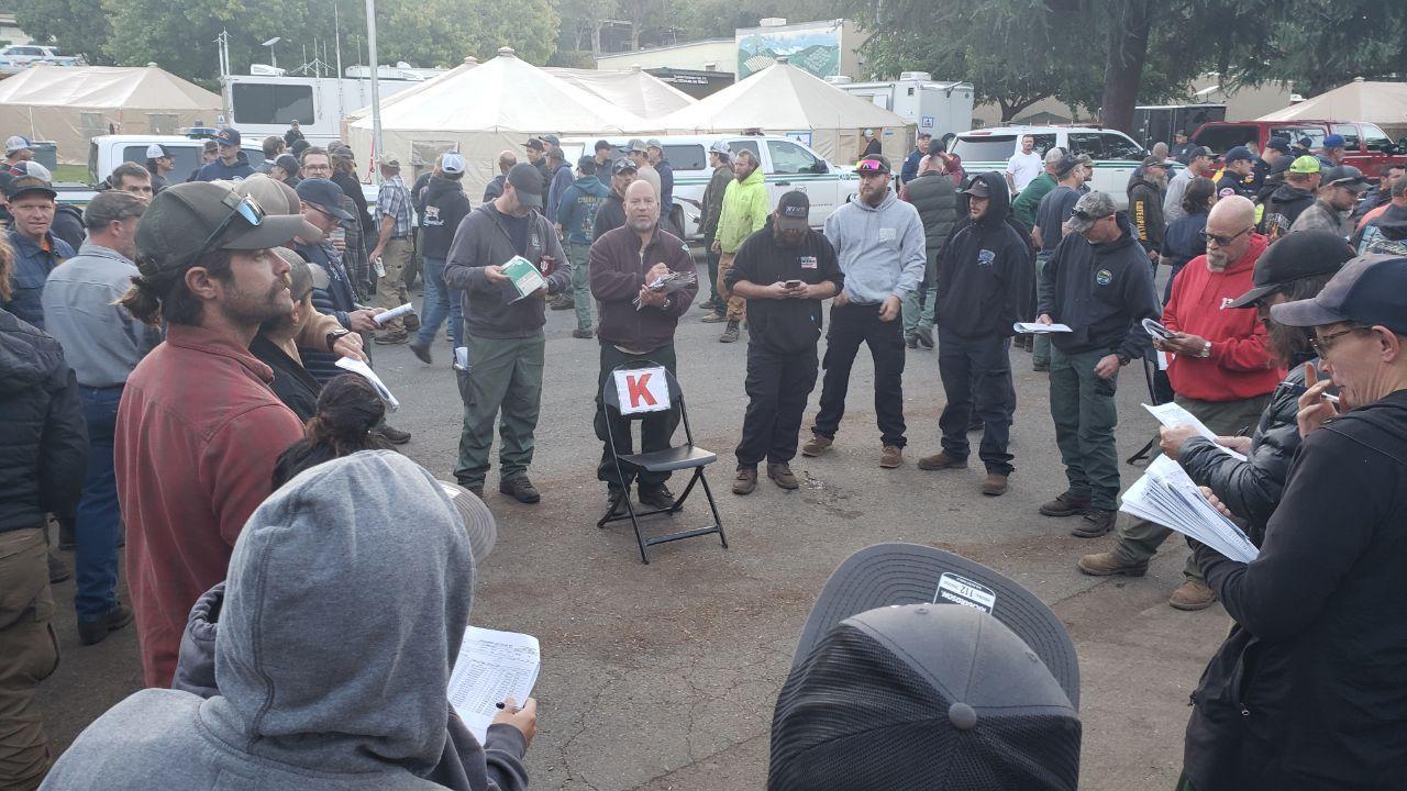 Firefighters gather around to discuss tactics during a morning briefing on the Mosquito Fire. Each morning, personnel receive a briefing from the command staff. They will then break into smaller groups, depending on their assignment, and discuss the plan 