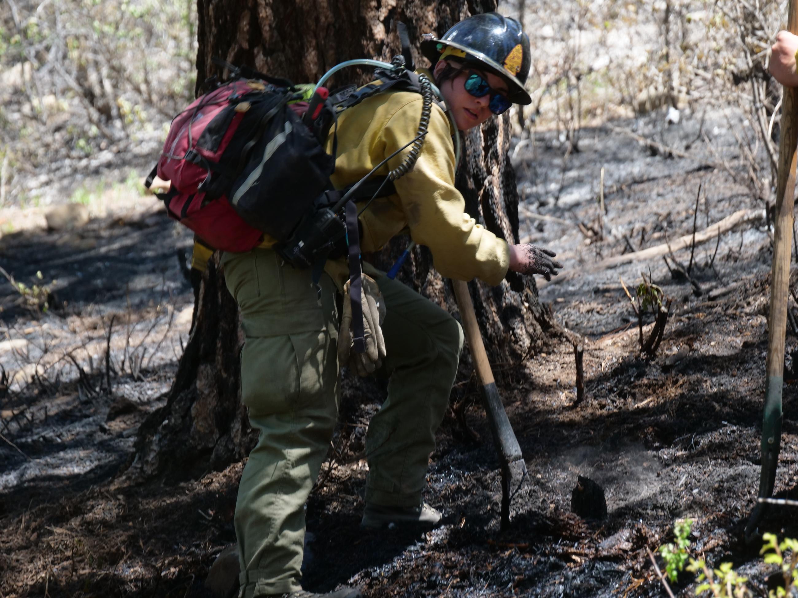 A firefighter is shown "mopping up" during a prescribed burn on the San Juan National Forest.