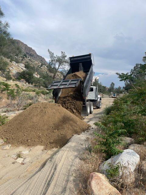 dump truck drops a load of fill material onto a road on the Sequoia National Foreste.