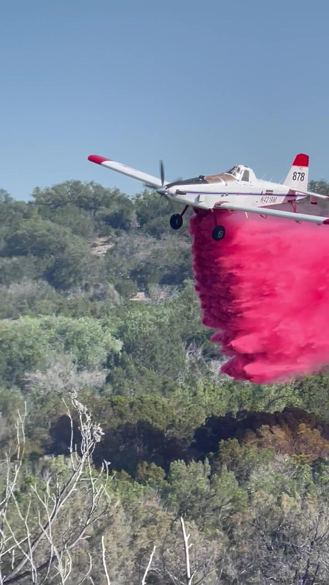 T-878 plane dropping flame retardant over vegetation